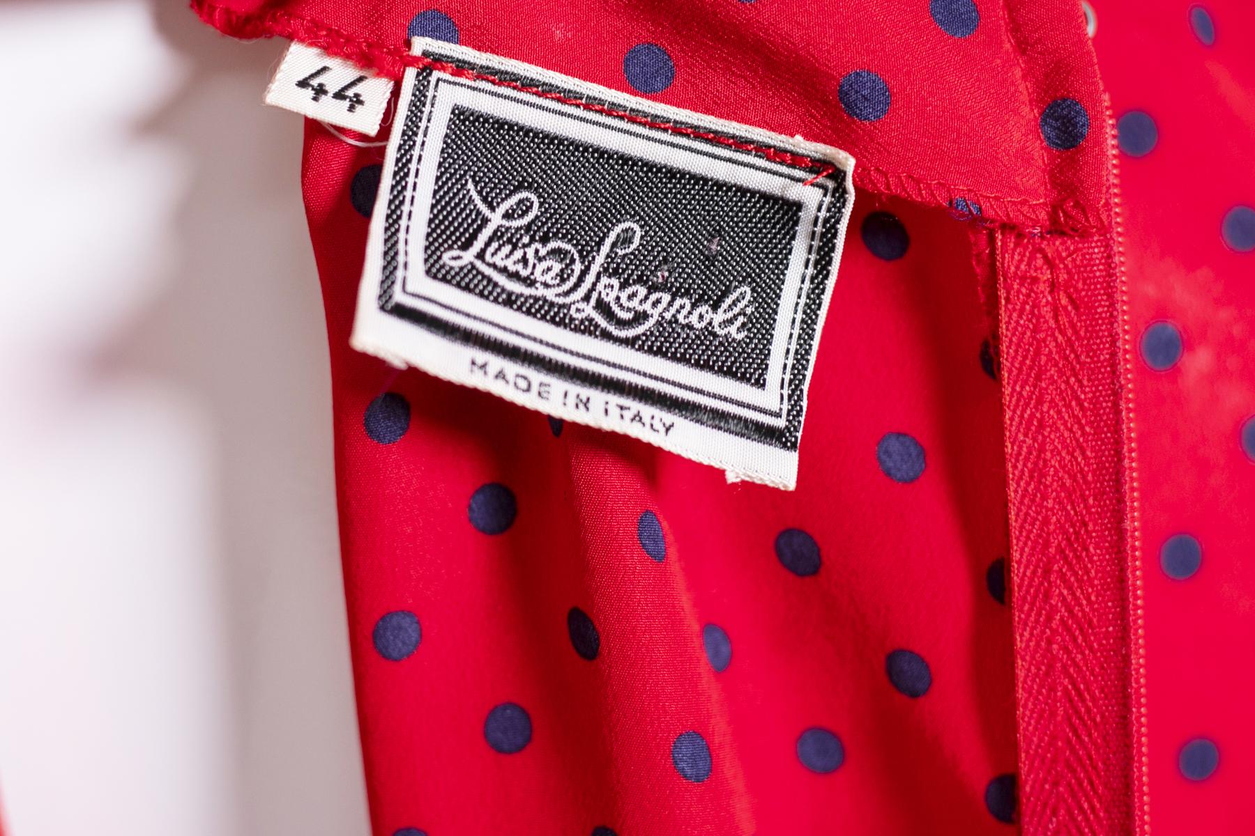 Schöne Vintage-Kleid unterzeichnet Luisa Spagnoli, rote Farbe Hintergrund und kleine blaue Pois.
Das Kleid Luisa Spagnoli ist 80er Jahre Stil, hat einen 