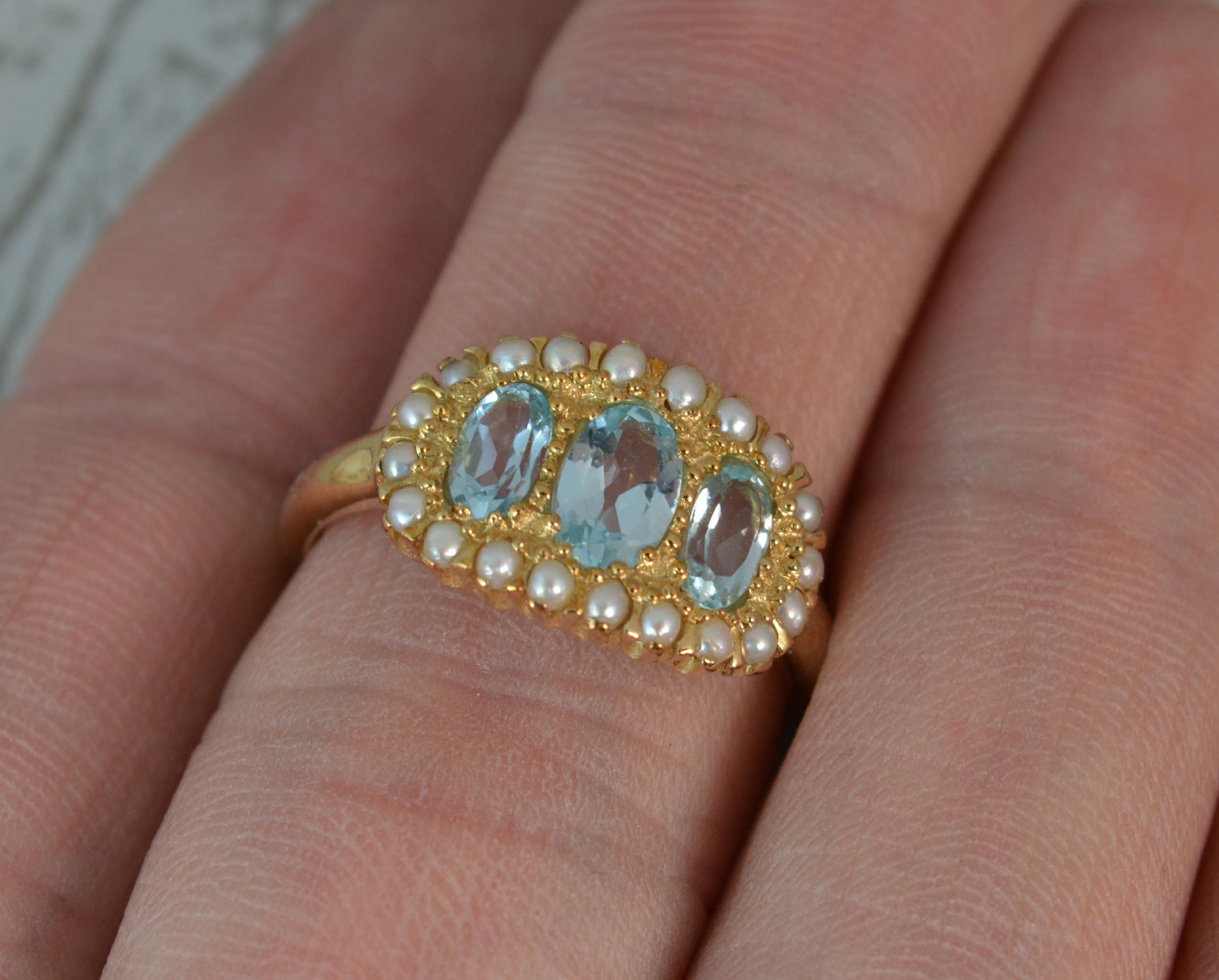 A LUKE STOCKLEY Designer ring. Solid 9 carat yellow gold example. 
Size ; N UK, 6 1/2 US
Three oval cut aquamarine stones with full surround of seed pearls.
15mm x 10mm cluster head.

Condition ; Excellent. Clean, solid shank. Well set stones.