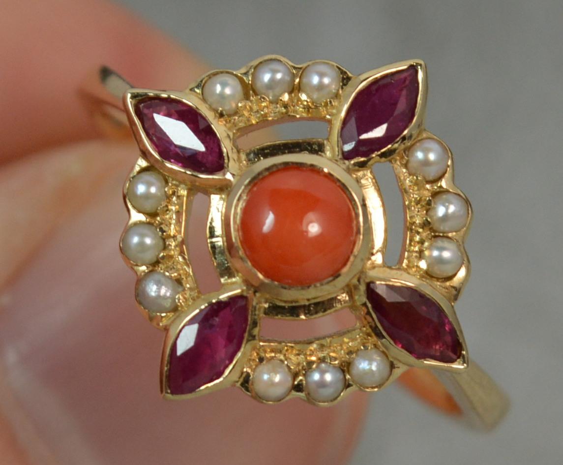 A LUKE STOCKLEY Designer ring. Solid 9 carat yellow gold example. 
Size ; N 1/2 UK, 7 US
Round coral to centre with halo of pearls and marquise cut ruby stones surrounding.
15mm x 15mm cluster head.
Condition ; Excellent. Clean, solid shank. Well
