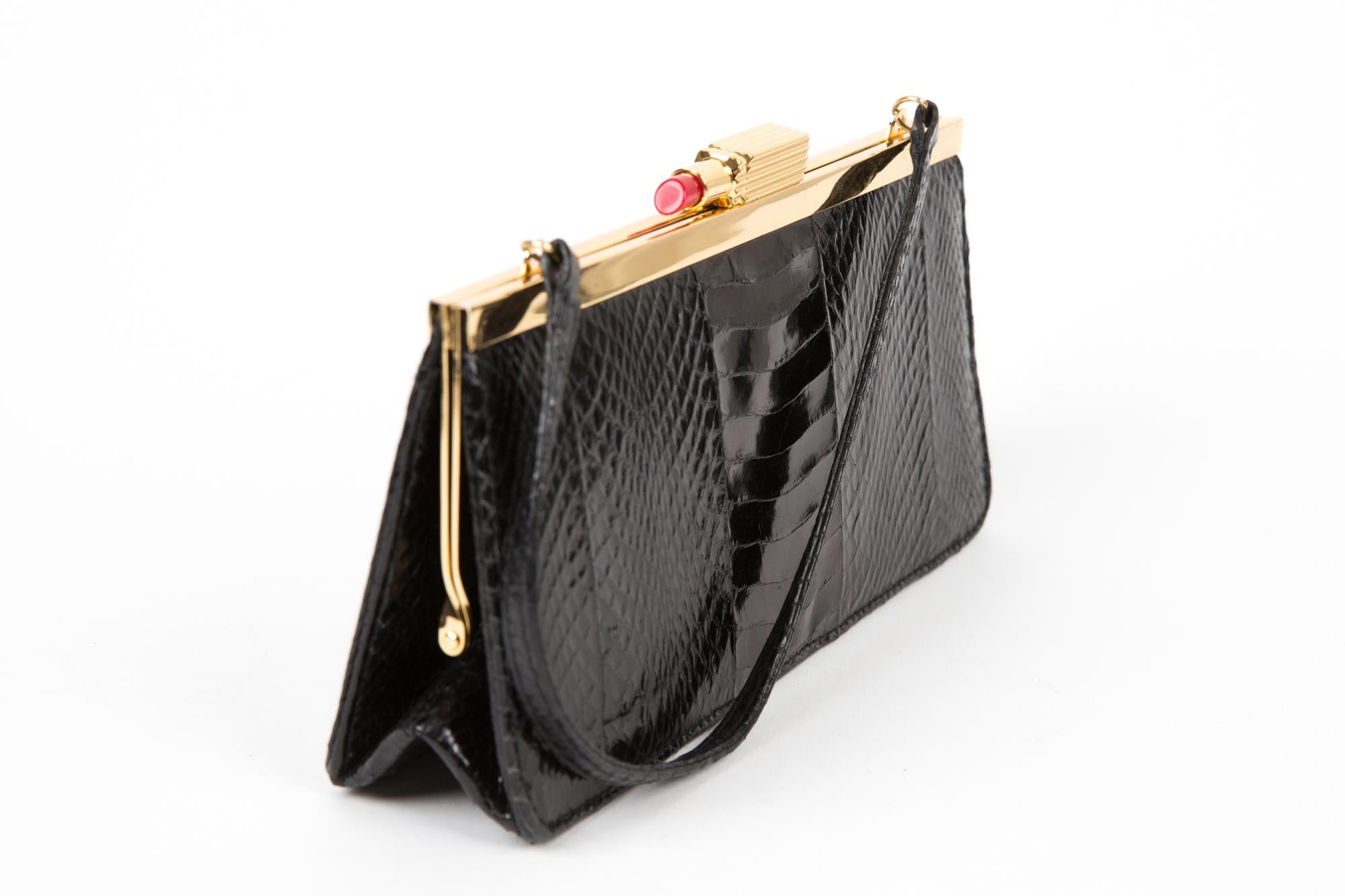 Lulu Guinness Black leather evening hand bag featuring a fancy top lipstick accessory closure, a top handle, gold-tone hardware, a message embroidered inside the bag.
Length : 9.4in (24cm)
Height: 4.3in. (11cm)
Width:1.5in. (4cm)
In good vintage