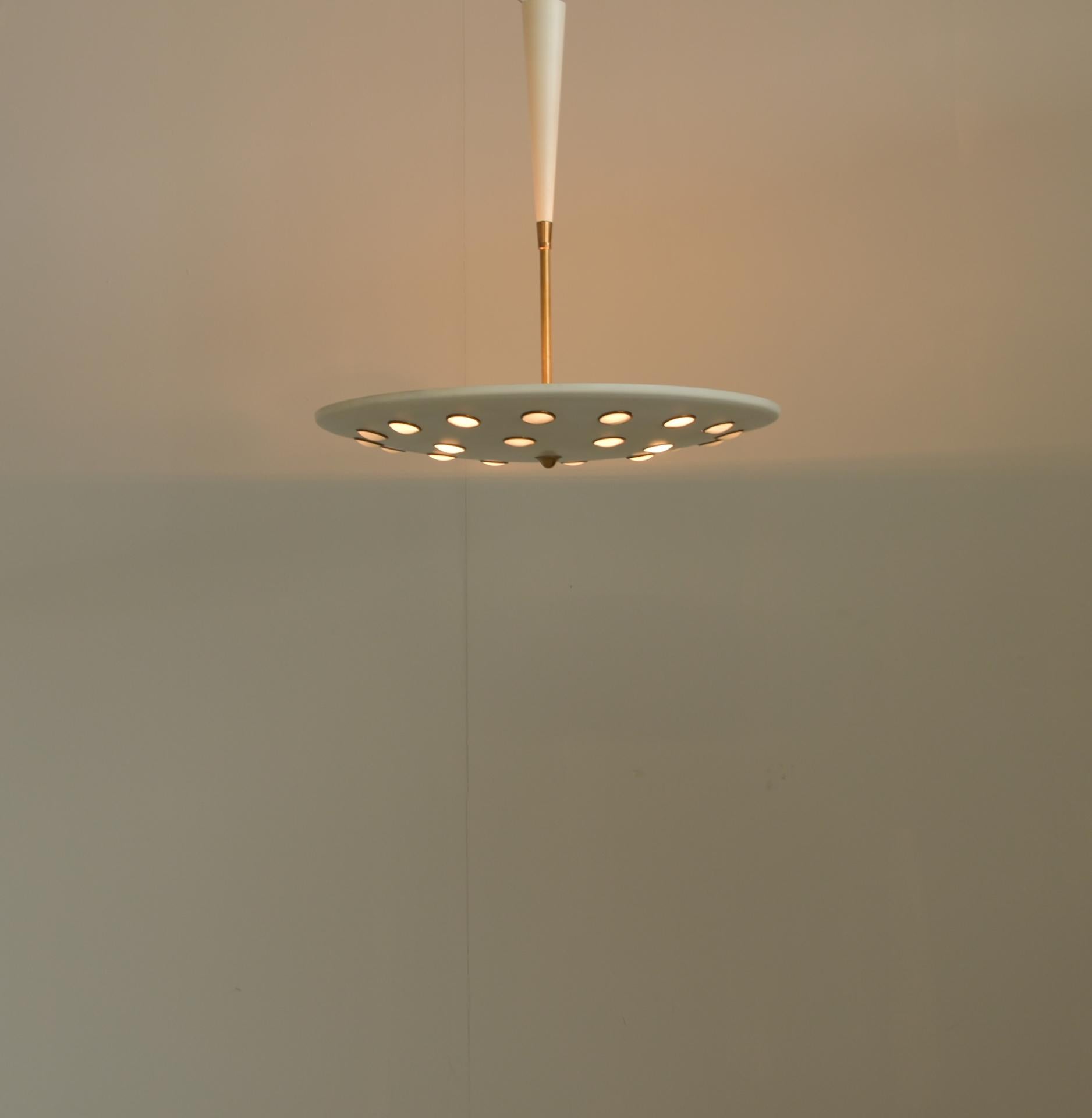 Lumen Milano midcentury Italian pendant lamp, circa 1950. Lacquered metal pendant light with a suspended dish indented with inserted brass circles and semi opaque glass lenses.