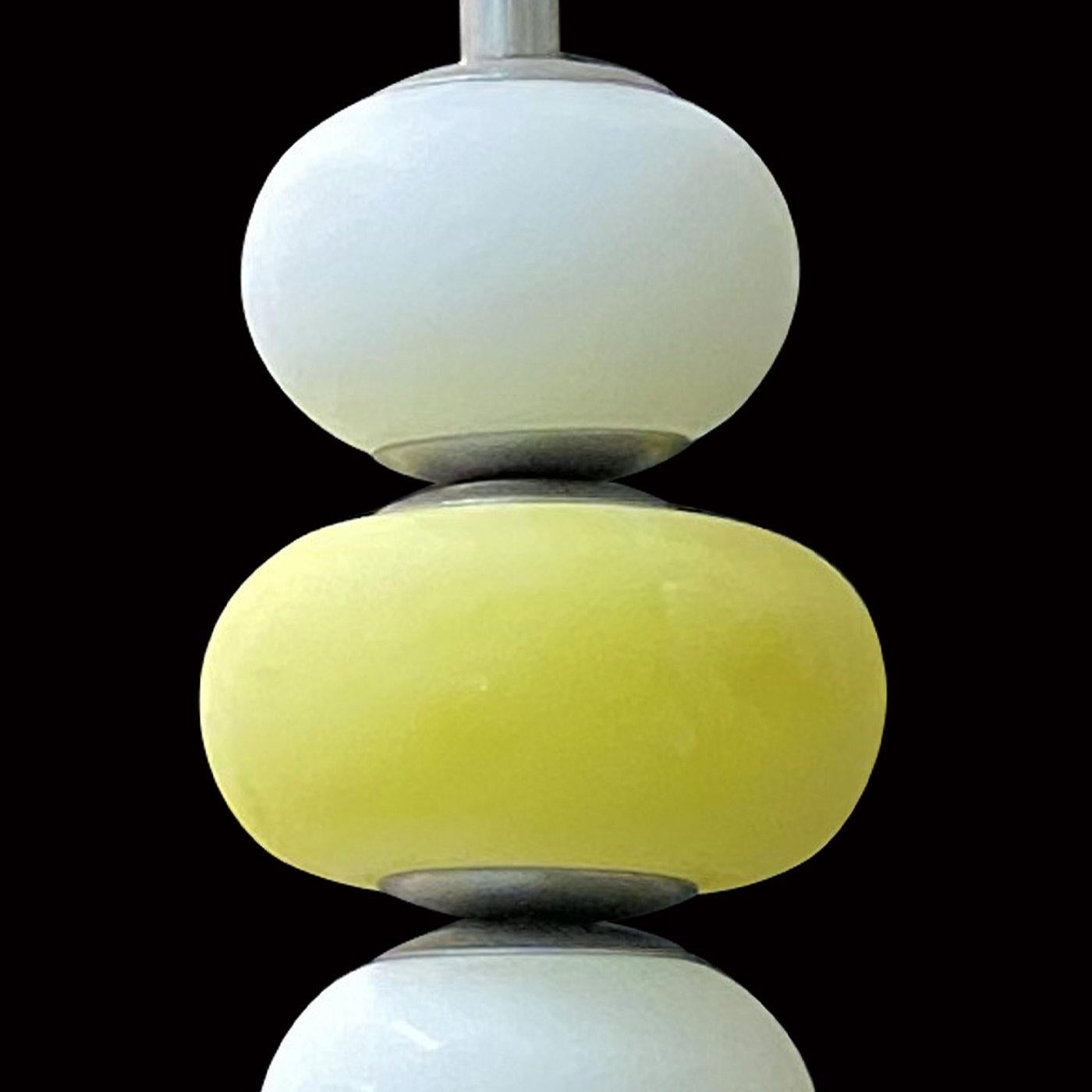 Bulging volumes with flattened poles and fashioned of sandblasted glass define the orderly and fresh look of this pendant lamp, eye-catching addition to any modern decor. Alternating white and bright yellow spheres, the design enhances its