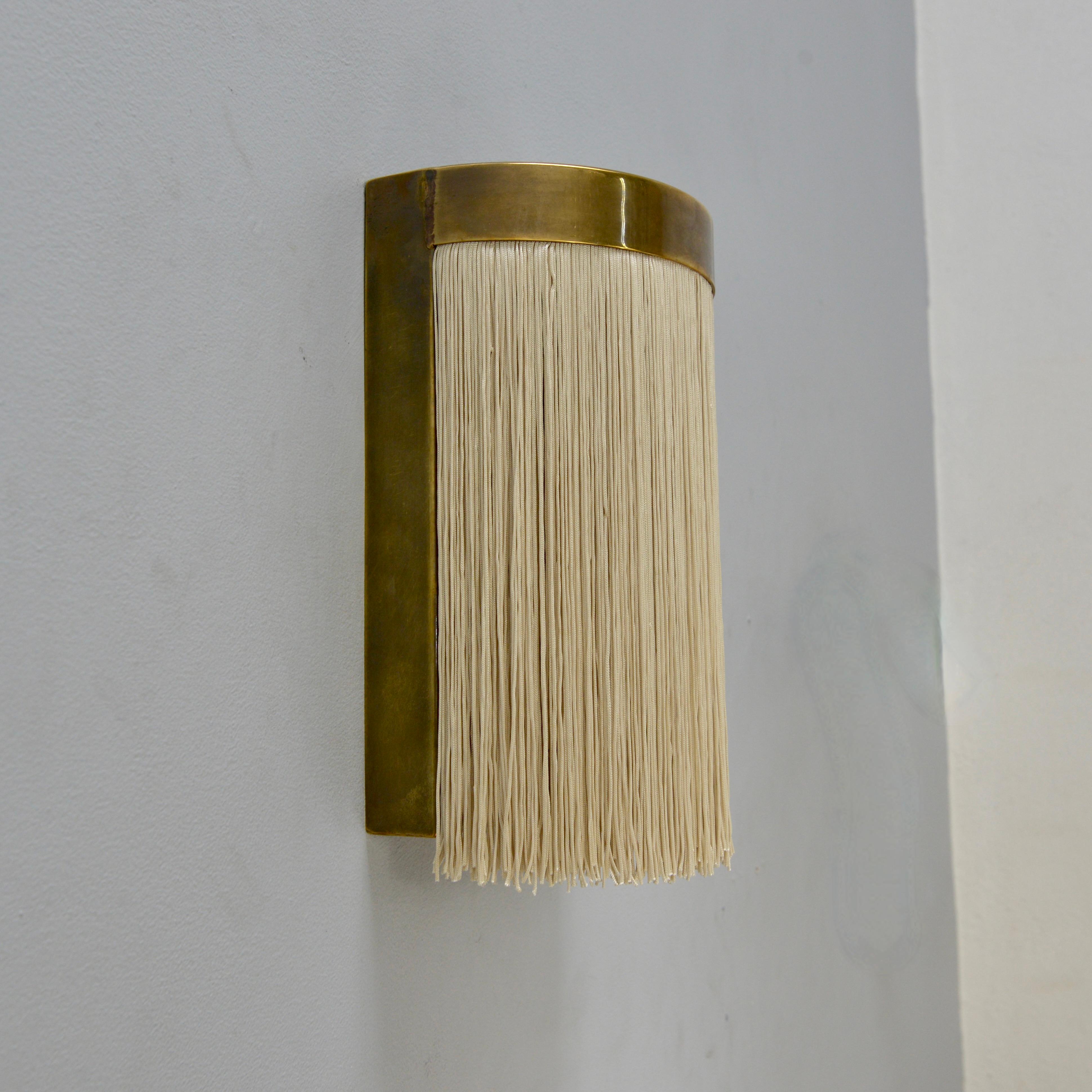 The fantastic LUMfk Sconce is a patinated brass and champagne toned fringe wall sconce inspired by mid century Italian design. This sconce is created by Lumfardo Luminaires and made contemporary in the US. Multiples available for order. Can be wired