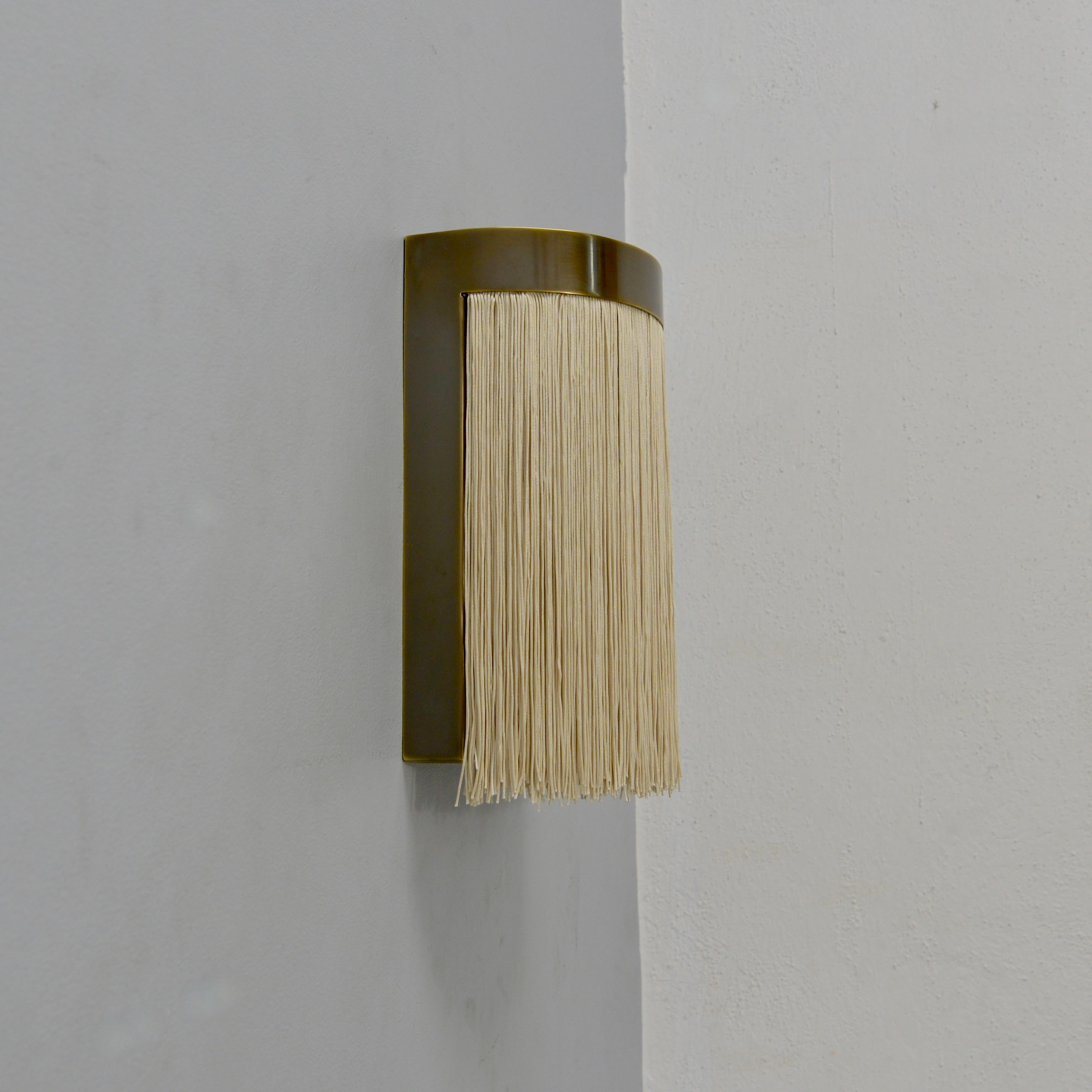 El fantástico Aplique LUMfr es un aplique de latón patinado y flecos en tono champán inspirado en el diseño italiano de mediados de siglo. Este candelabro ha sido creado por Lumfardo Luminaires y es de fabricación contemporánea en EE.UU. Múltiplos