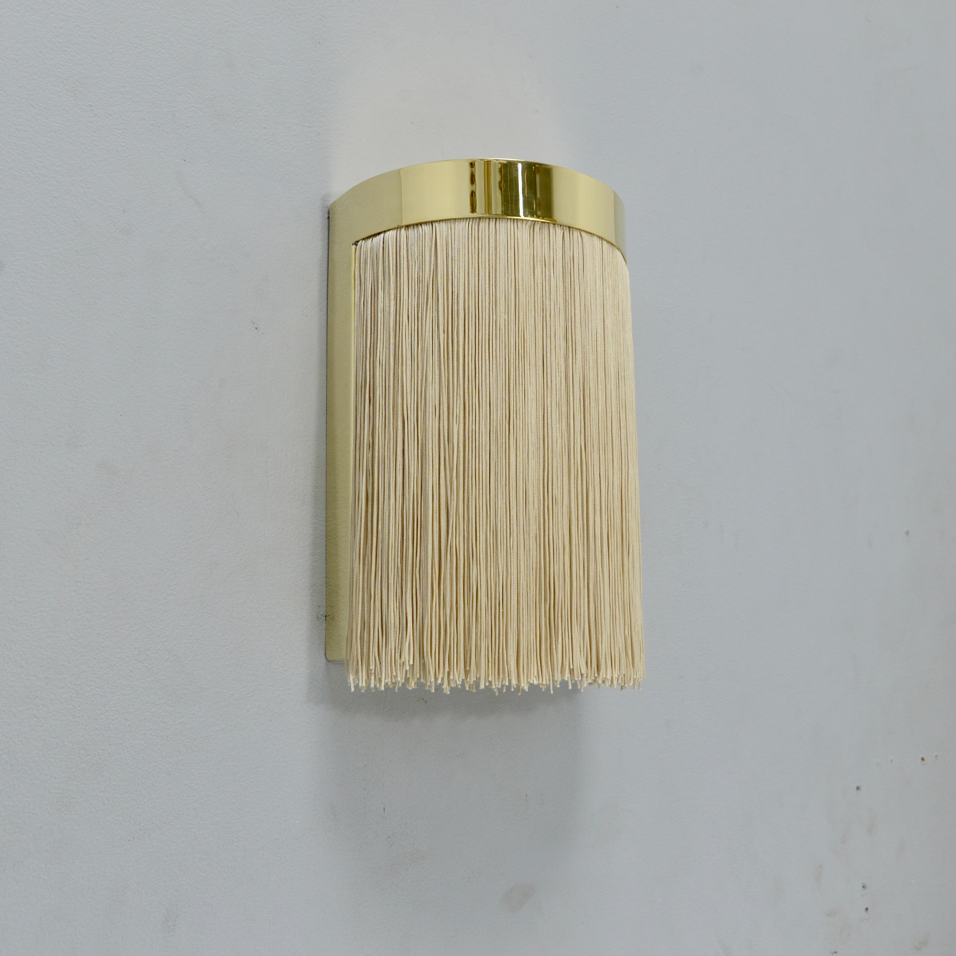 El fantástico aplique LUMfr es un aplique de pared de latón pulido sin lacar y flecos en tono champán inspirado en el diseño italiano de mediados de siglo. Este candelabro ha sido creado por Lumfardo Luminaires y es de fabricación contemporánea en