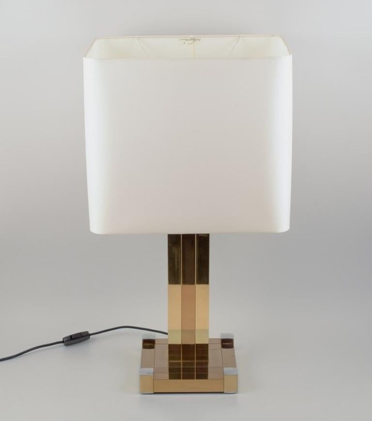 Lumica, España. Lámpara de mesa grande. 
Vástago y pie de metal dorado con detalles cromados. Pantalla de tela blanca.
En perfecto estado.
Finales del siglo XX
Marcado.
Dimensiones: H 73,0 cm. con pantalla.
Pantalla: L 40 x P 31,0 x Alt 35,0