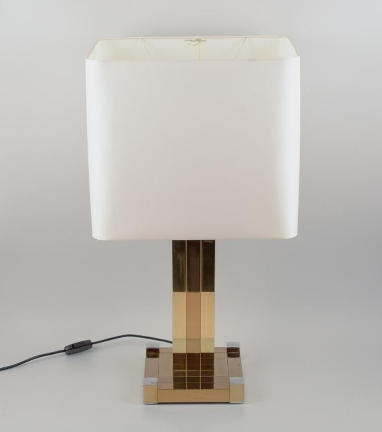 Lumica, Spain. Large table lamp. 
Stem and foot in gold-plated metal with chrome-plated details. Screen in white fabric.
In perfect condition.
Late 20th century
Marked.
Dimensions: H 73.0 cm. with screen.
Screen: L 40 x D 31.0 x H 35.0 cm.