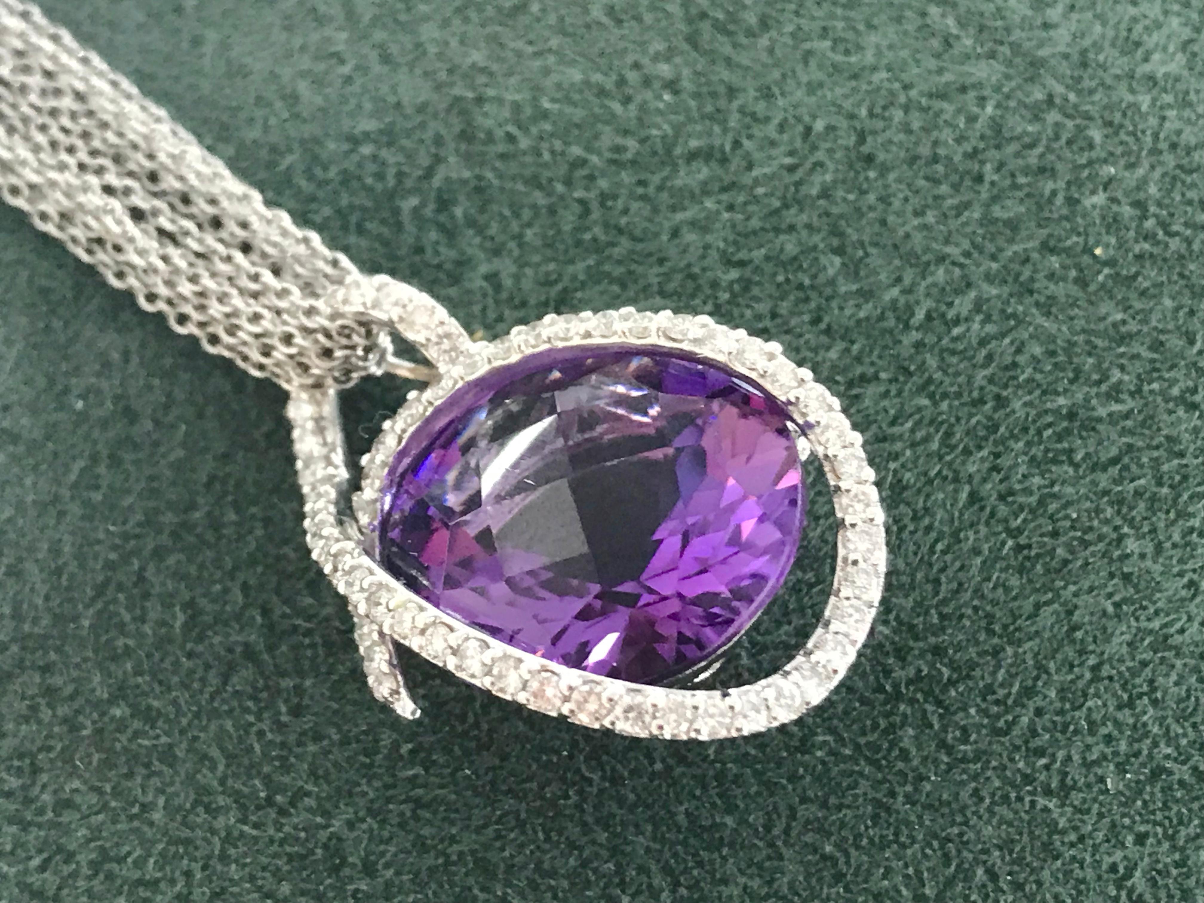 18K white gold large faceted amethyst wrapped in a diamond ribbon. The amethyst weighs 18.00 carats and the diamonds weigh combined 0.95 carat. The pendant hangs on a 7 strand 18K white gold chain.