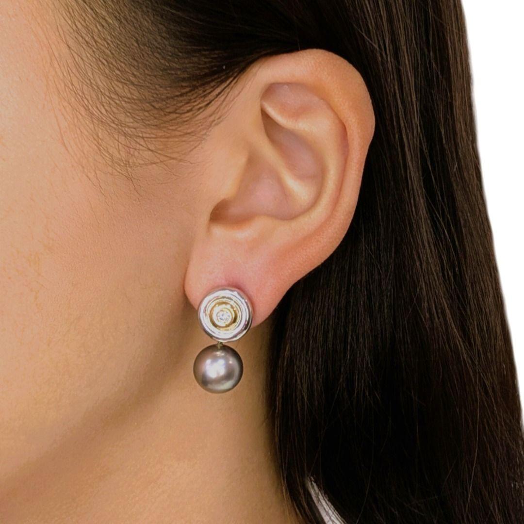 Estos pendientes, un sorprendente equilibrio de elegancia y arte, presentan dos perlas redondas de los Mares del Sur de 10,42 mm cada una, que brillan con un refinado lustre gris que irradia un lujo discreto. Acentuando las perlas hay dos diamantes