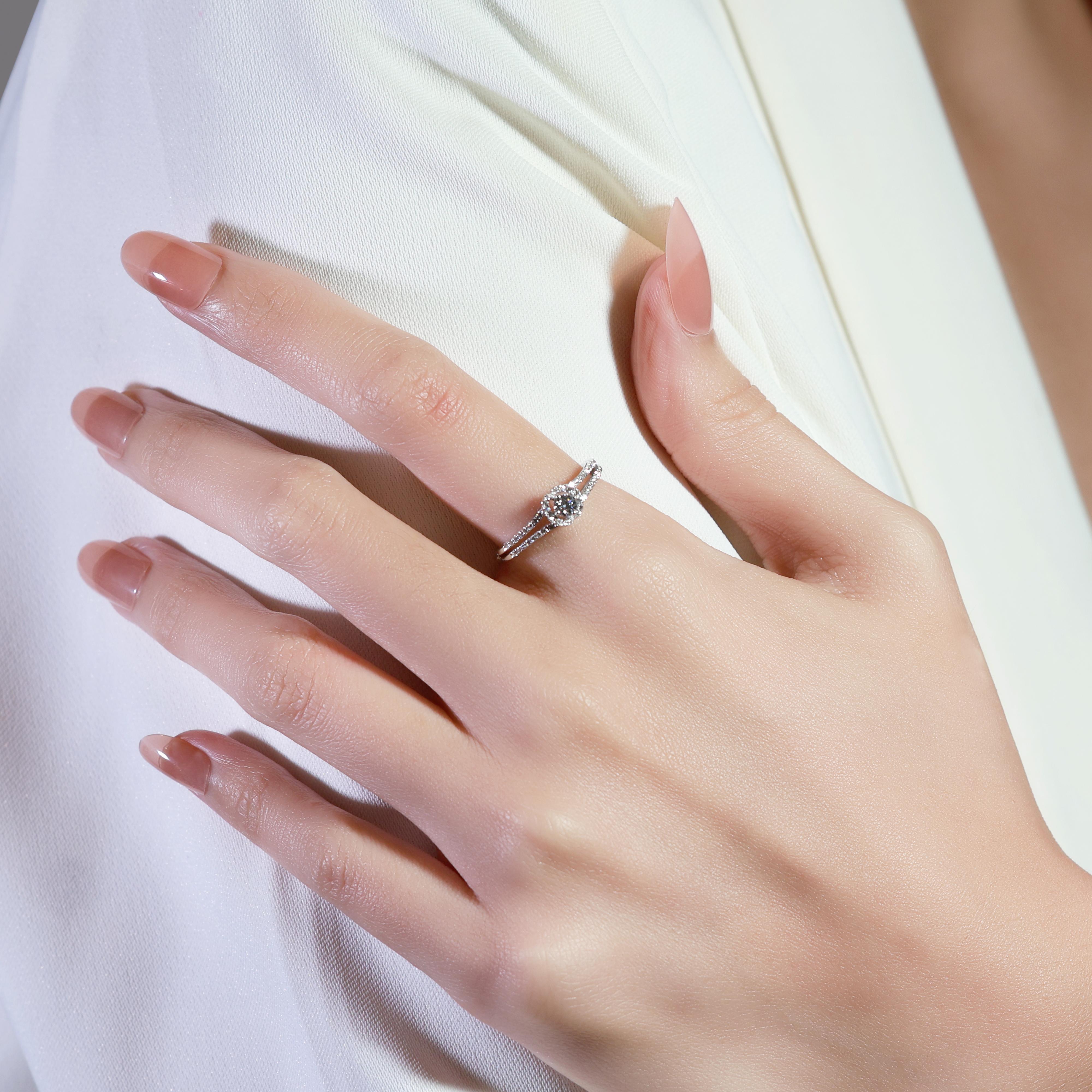 Crafted from 18K white gold, this elegant ring showcases a 0.13ct round brilliant diamond as the centerpiece, with a color grade of G and clarity grade of VS for exceptional sparkle and quality. Enhancing the beauty of the main diamond are 46 round