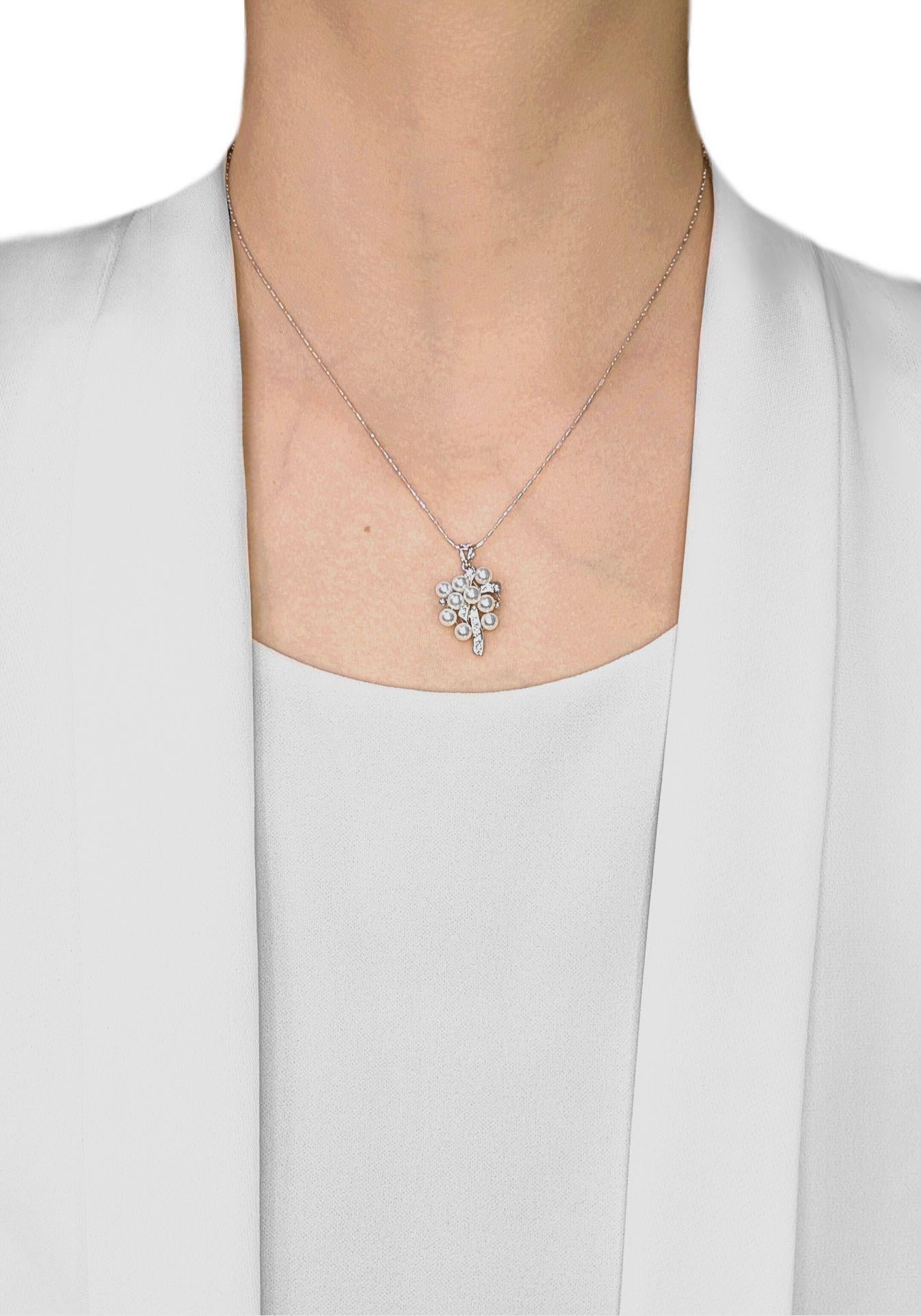 Ce superbe pendentif est un gracieux mélange de luxe et de charme, réalisé en or blanc 18 carats et orné de neuf perles d'Akoya lustrées (4 mm chacune) aux douces nuances de rose et de blanc. Les perles forment une grappe rayonnante, rehaussée par