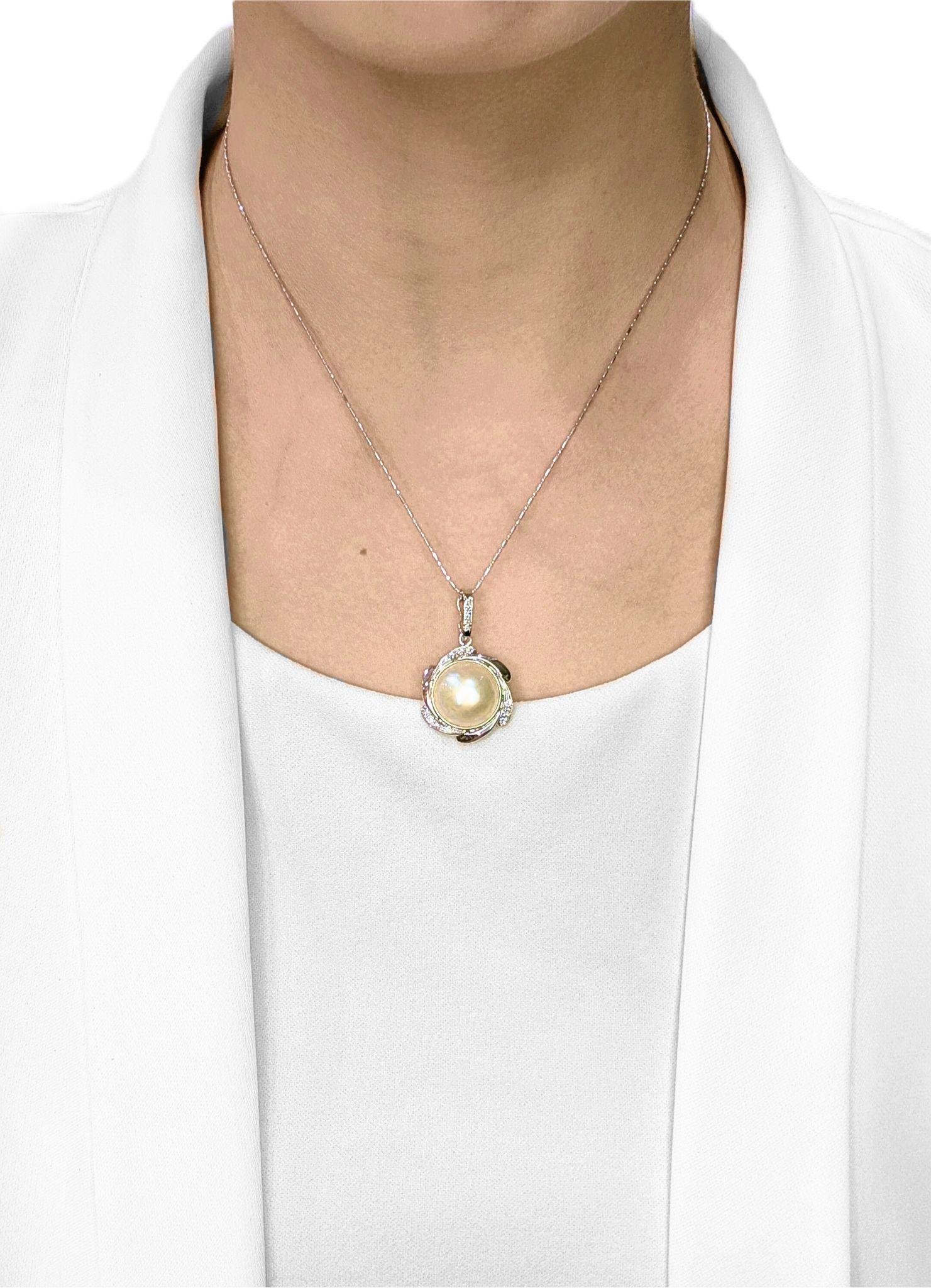 This new pendant radiates soft elegance, featuring a luminous 14 mm champagne-hued Mabe pearl embraced by a swirling 18K white gold setting. Fourteen round brilliant diamonds (0.28 ct total, F-G color, VS-SI clarity) are delicately embedded