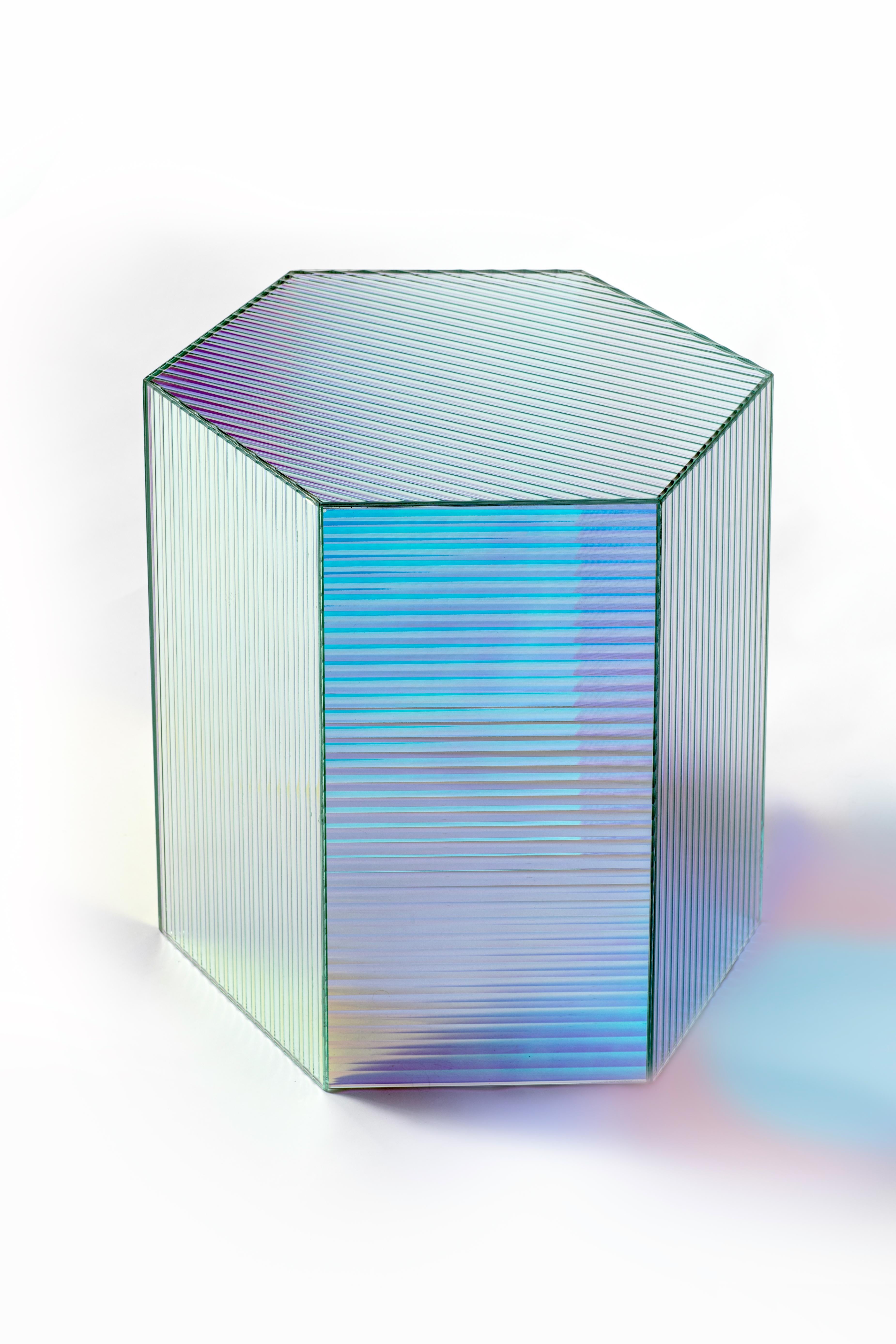 Luminous Side Table by Yugen Lab
Dimensions: D 40 x W 45 x H 46 cm.
Materials: 4 mm ribbed glass.

Luminous is a ribbed glass piece with an iridescent design, showcasing a dazzling array of colors when illuminated. Its versatile design allows it to