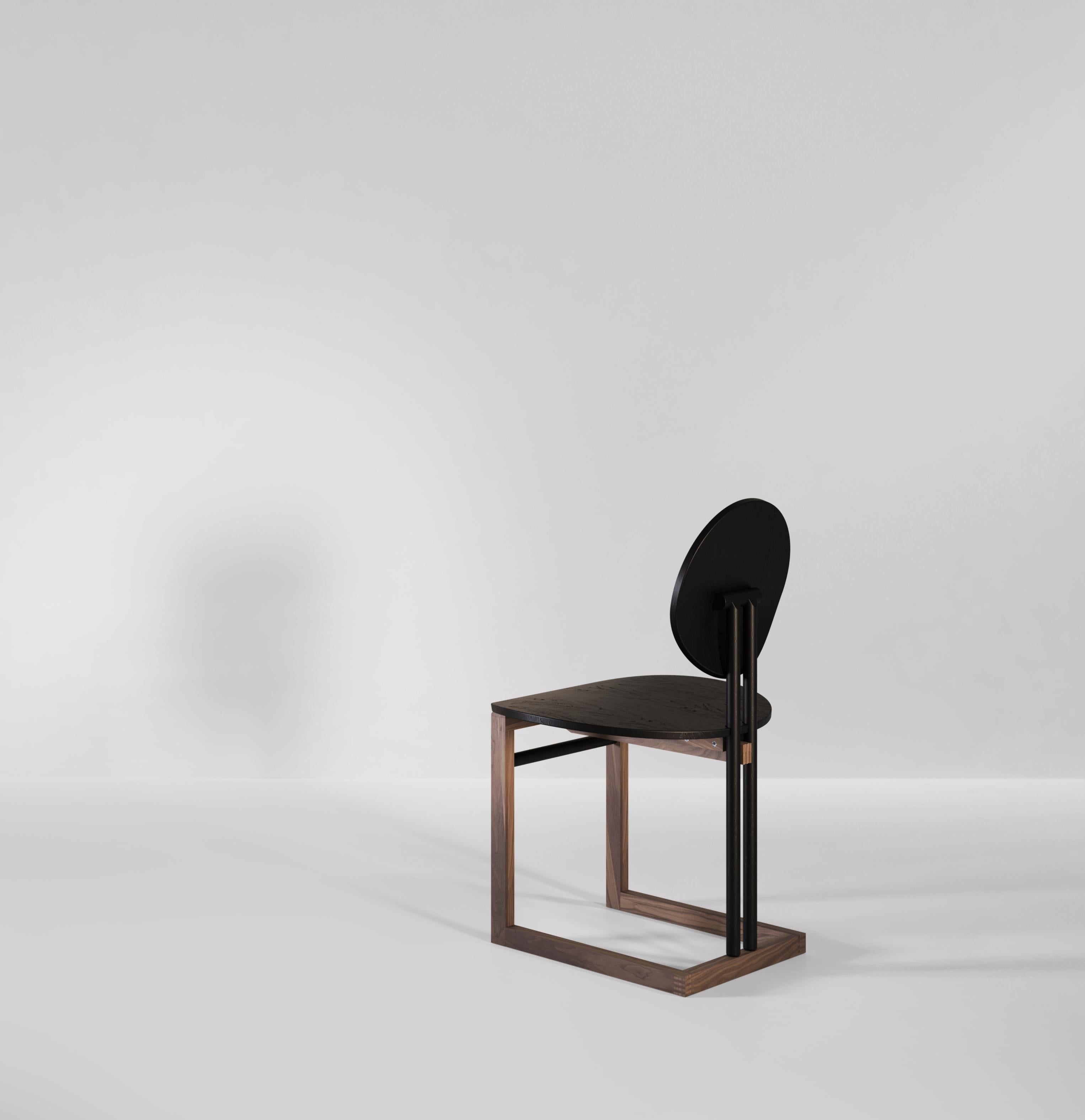 Ein handgefertigter Esszimmerstuhl aus Holz, inspiriert von Vintage-Formen und zeitgenössischen Techniken. Zwei Fast-Kreise, die als Rückenlehne und Sitz dienen, bieten Komfort und Stil. Die Struktur, die den Stuhl hält, ist aus einem