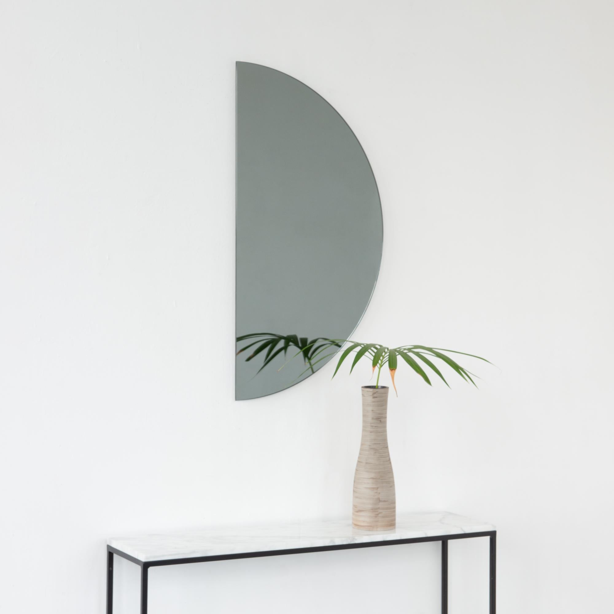 Minimalist half-moon Luna™ black tinted frameless mirror with a floating effect. Fitted with a quality and ingenious hanging system for a flexible installation in 4 different directions. Designed and made in London, UK. 

The backing has a brand new
