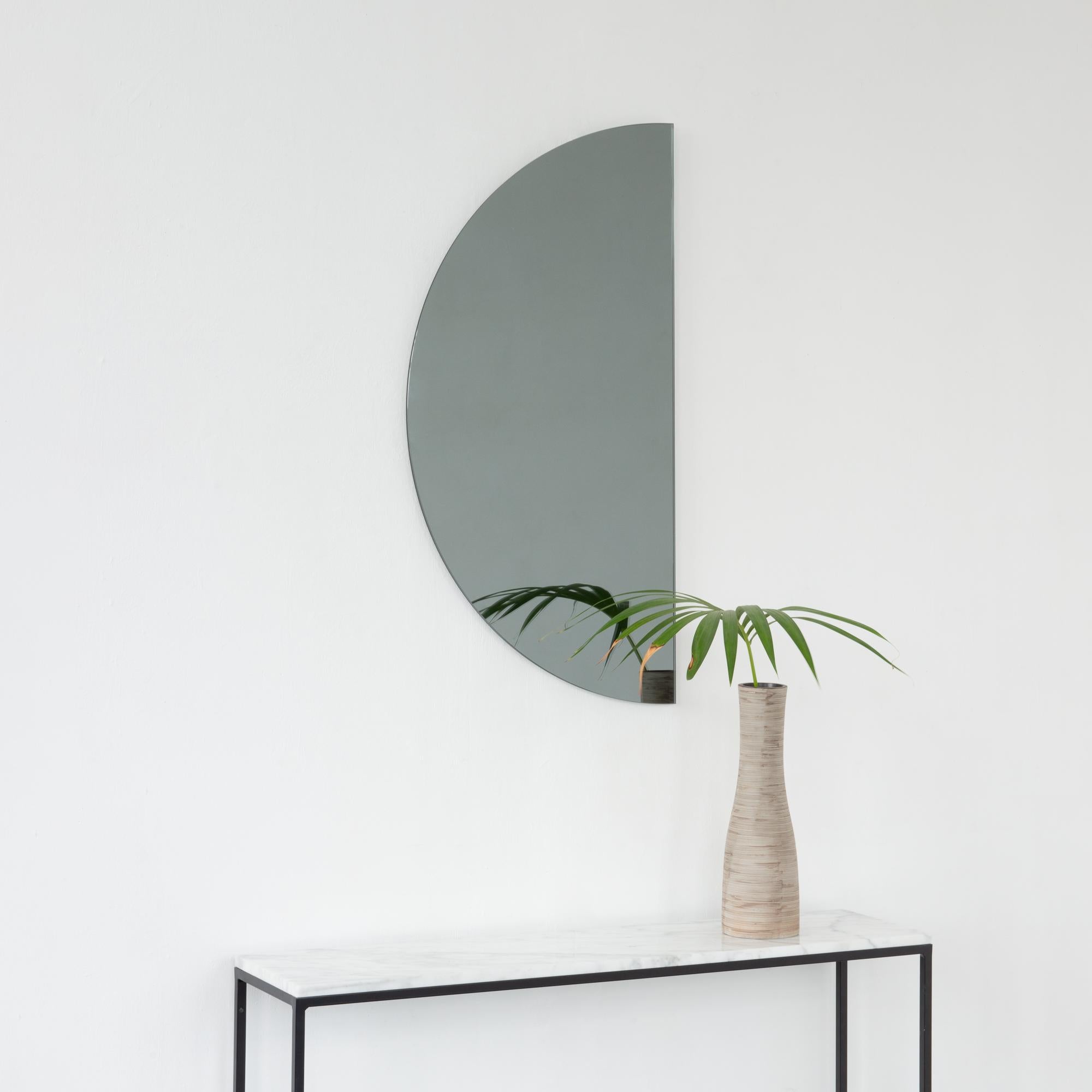 Minimalist half-moon Luna™ black tinted frameless mirror with a floating effect. Fitted with a quality hanging system for a flexible installation in 4 different directions. Designed and made in London, UK. 

Our mirrors are designed with an