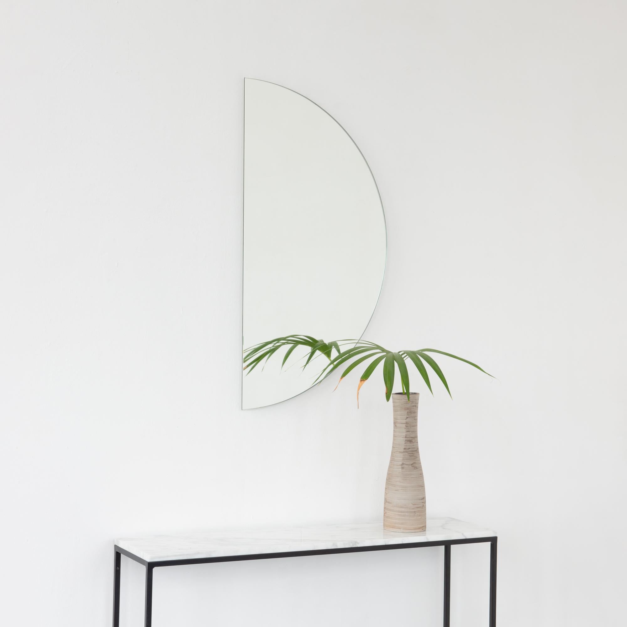 Minimalist Luna™ half-moon frameless mirror with a floating effect. Fitted with a quality and ingenious hanging system for a flexible installation in 4 different directions. Designed and made in London, UK.

The backing has a brand new design that