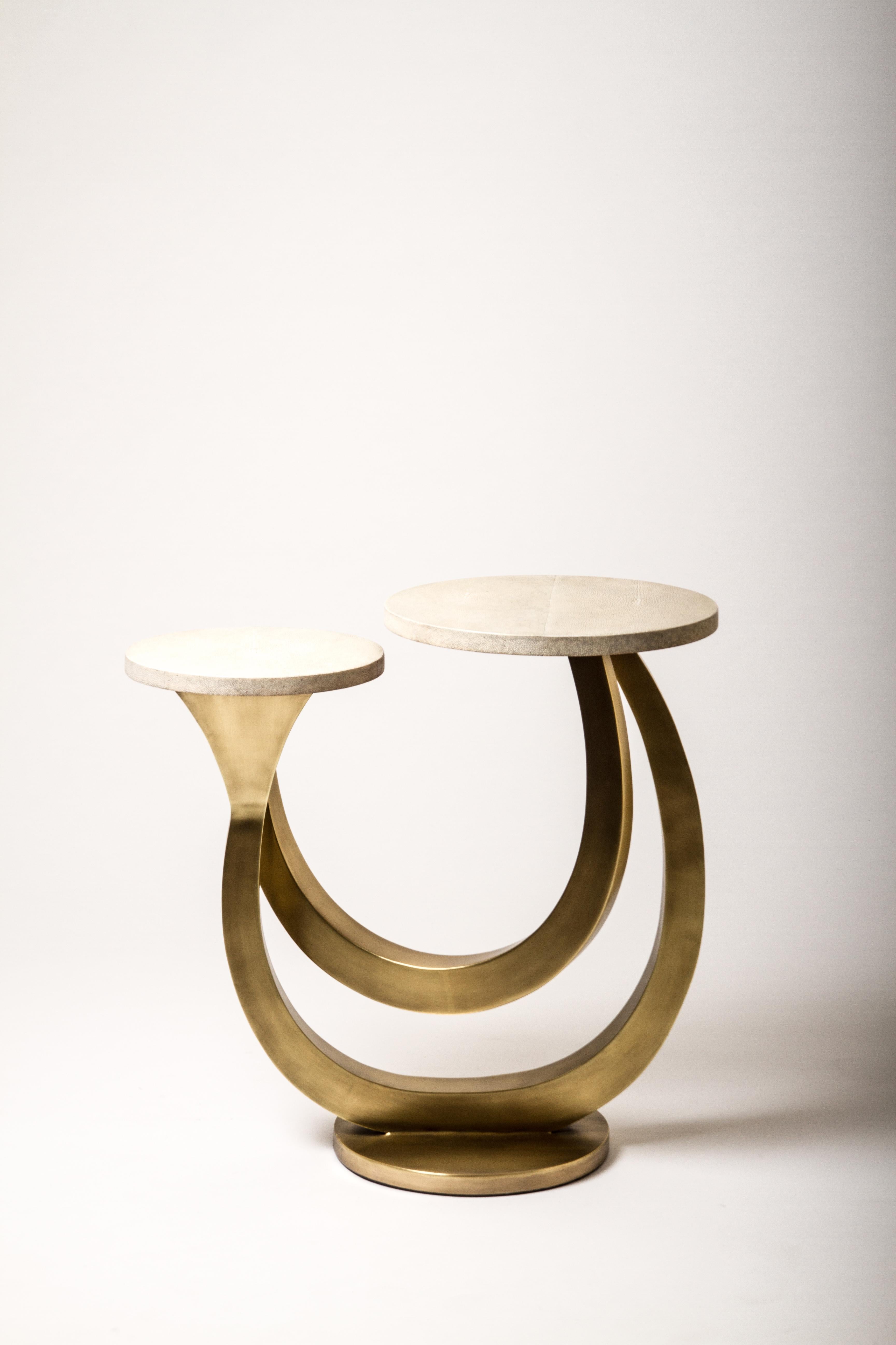 The Luna Side Table in cream shagreen is inspired by cosmic formations. The piece has two shagreen tops that rest at different levels, followed by bold bronze. A statement end table for any living space. The shagreen is hand-dyed by artisans and the