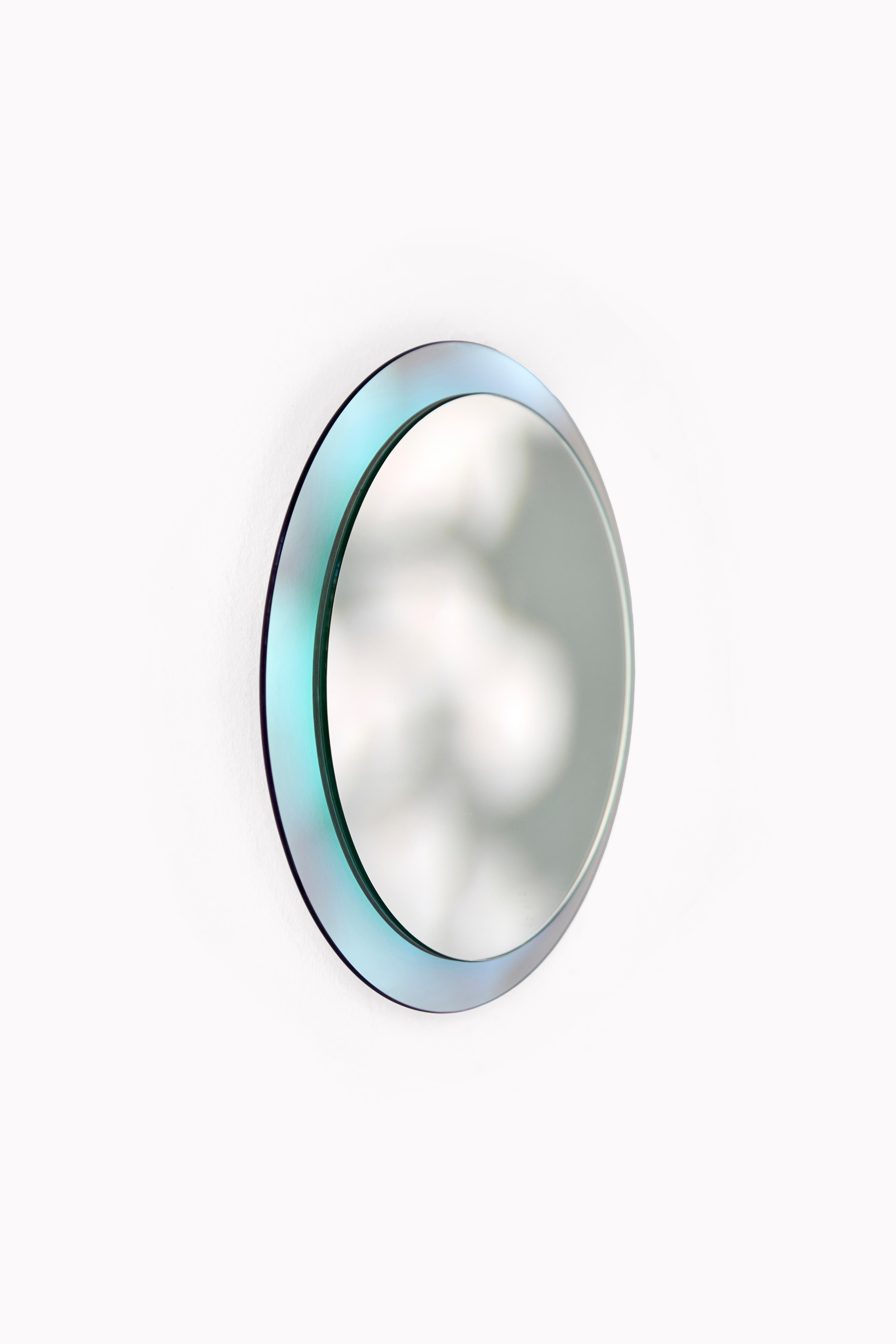 Luna Wall Mirror by Yugen Lab
Dimensions: Ø 35 cm.
Materials: 4mm mirror glass and 4mm iridescent glass.

Luna round mirror, sized at 35 centimeters in diameter, presents a 
captivating halo light that varies with the angle of incoming light,