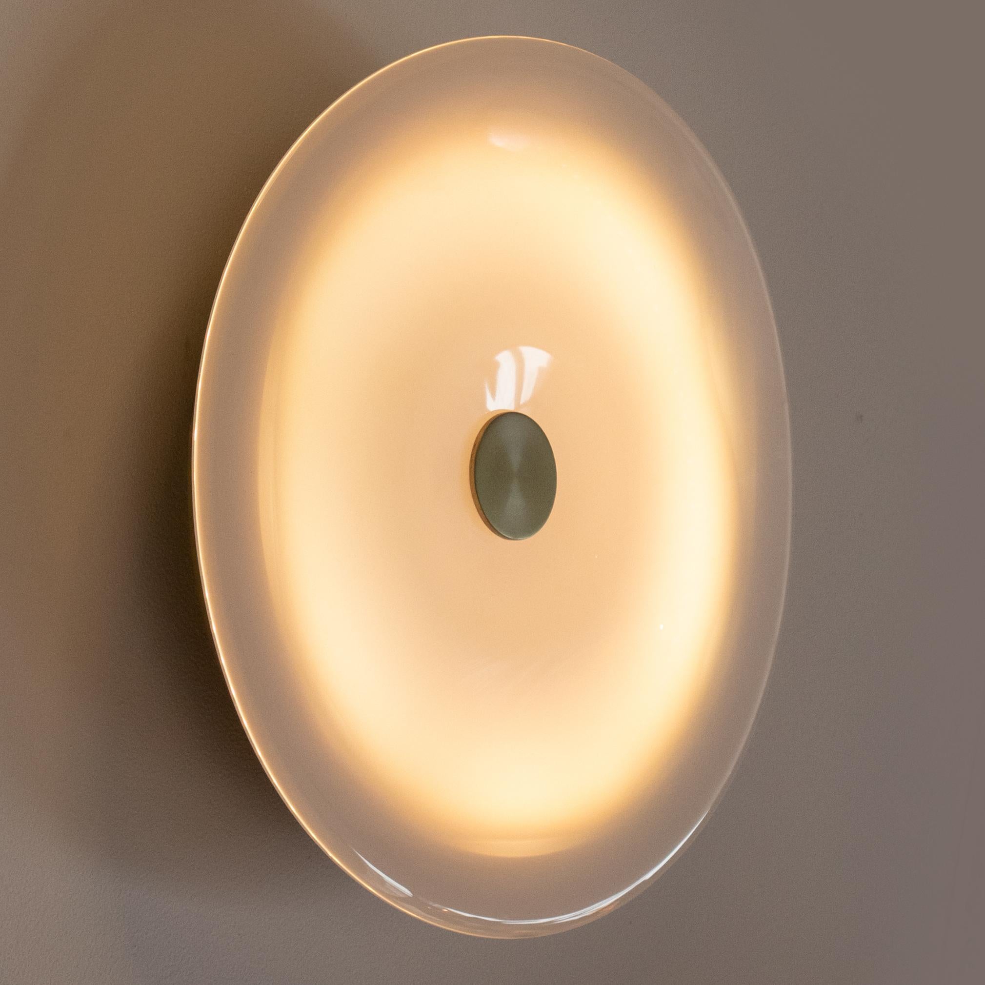 The LUNA wall sconce is built from cold rolled steel and features an undulated hand-blown glass disk diffuser. The glass disk is held in place by a solid brass ball on an articulating arm for adjustments. The sconce is back-lit with a warm white LED