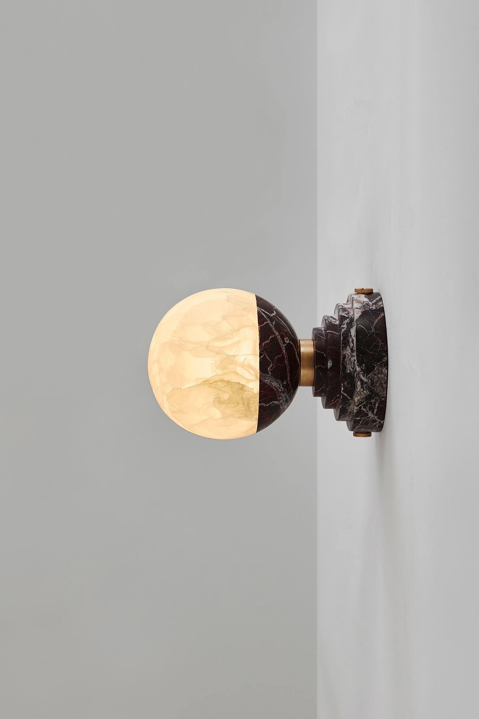 Cette ampoule lumineuse en onyx, qui éclaire l'espace d'une lumière chaude et douillette, est une déclaration d'amour à la lune argentée qui a inspiré tant de poètes et d'artistes. Posé sur un socle en marbre (disponible en Grand Antique, Portoro et