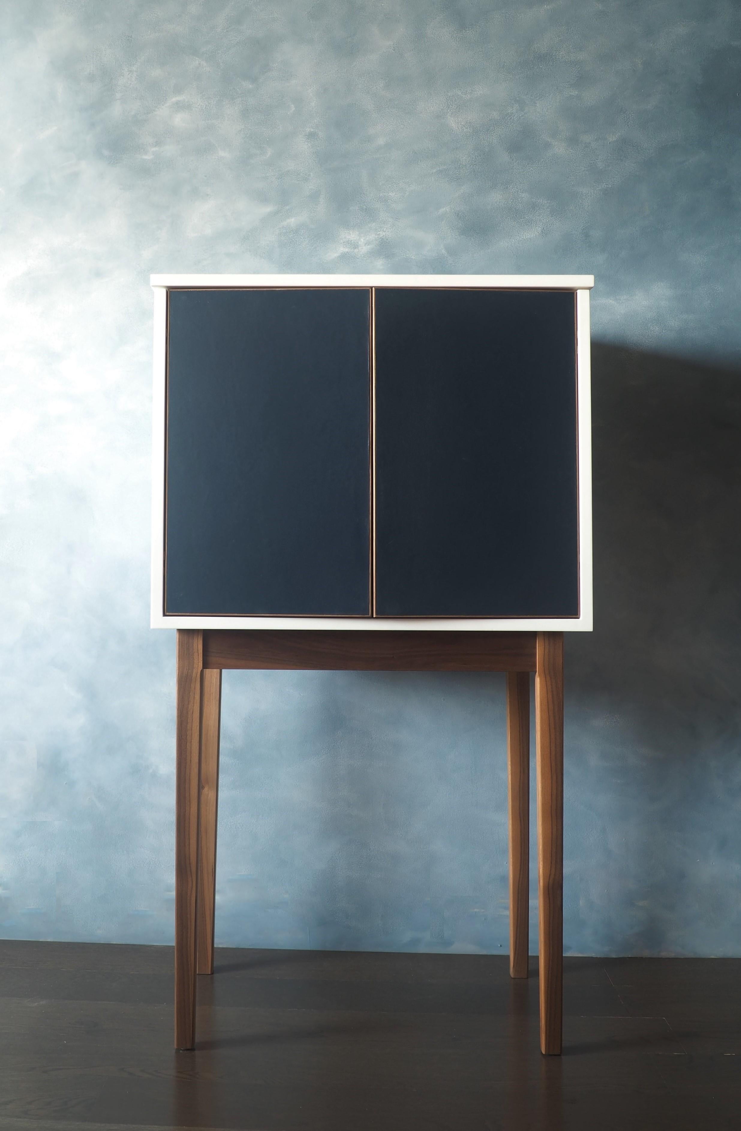 Our Lunar Eclipse liquor cabinet is made with solid walnut legs and solid walnut interior. The cabinet is white lacquer. The doors are midnight blue leather.

 It features an upper shelf for preparing your favorite cocktails. The left side features