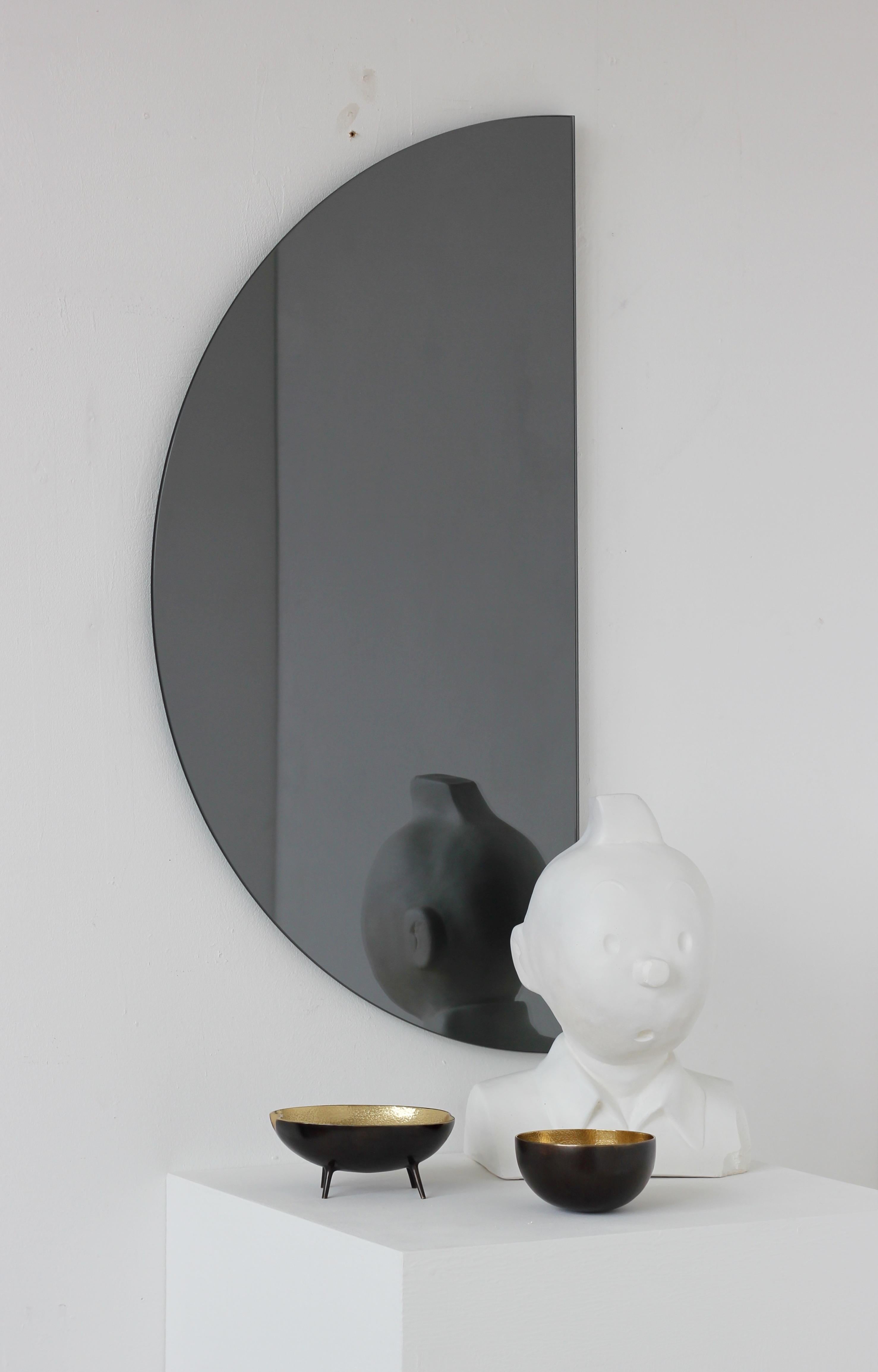 Original and minimalist half-moon black tinted frameless mirror with a floating effect. Quality design that ensures the mirror sits perfectly parallel to the wall. Designed and made in London, UK. 

Each piece is fitted with professional plates that
