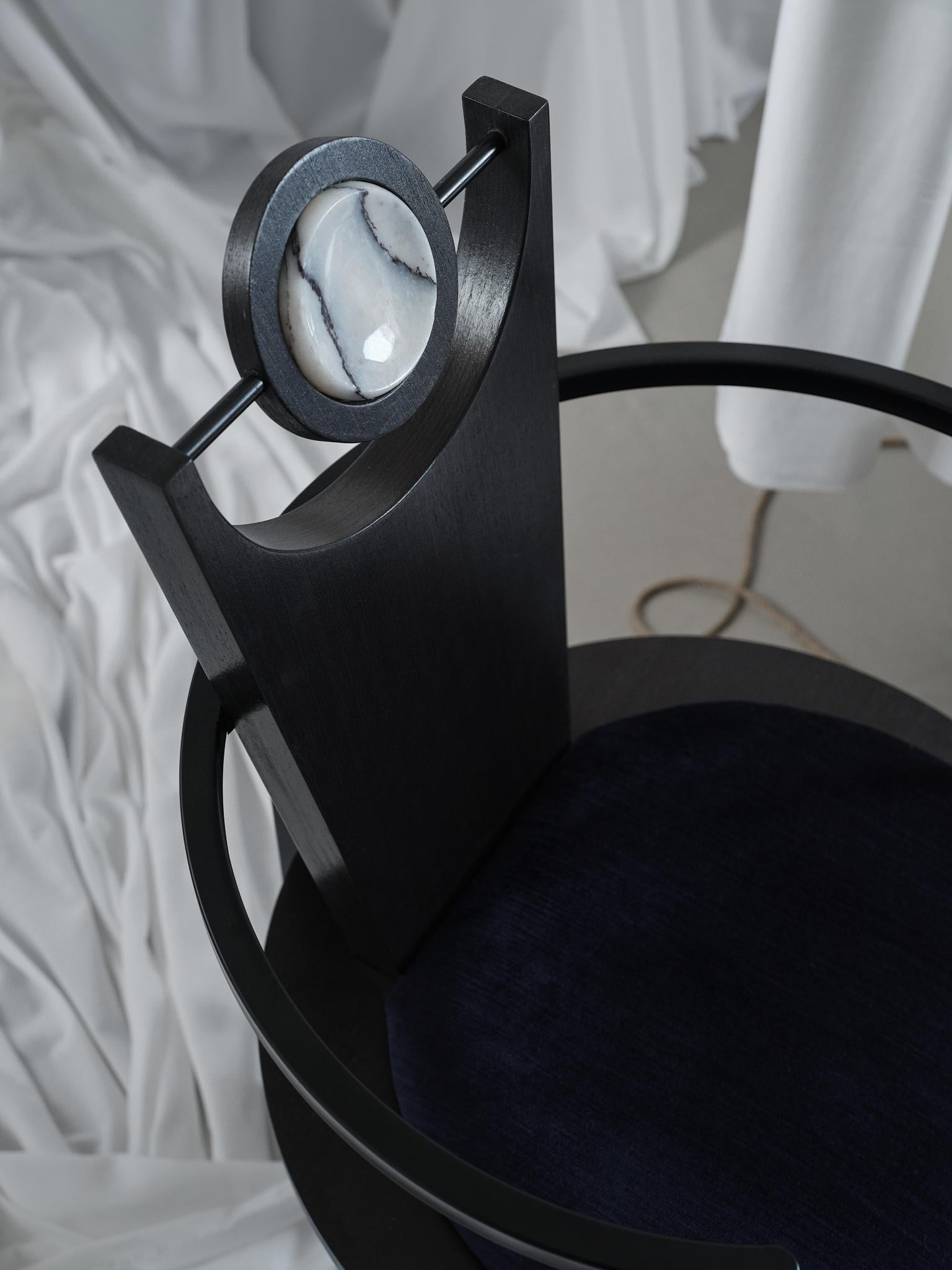 Esta llamativa silla es una mezcla perfecta de diseño contemporáneo y artesanía artística. Con una atrevida estructura geométrica, combina el elegante metal negro con la madera negra, creando un equilibrio de estética industrial y moderna. El