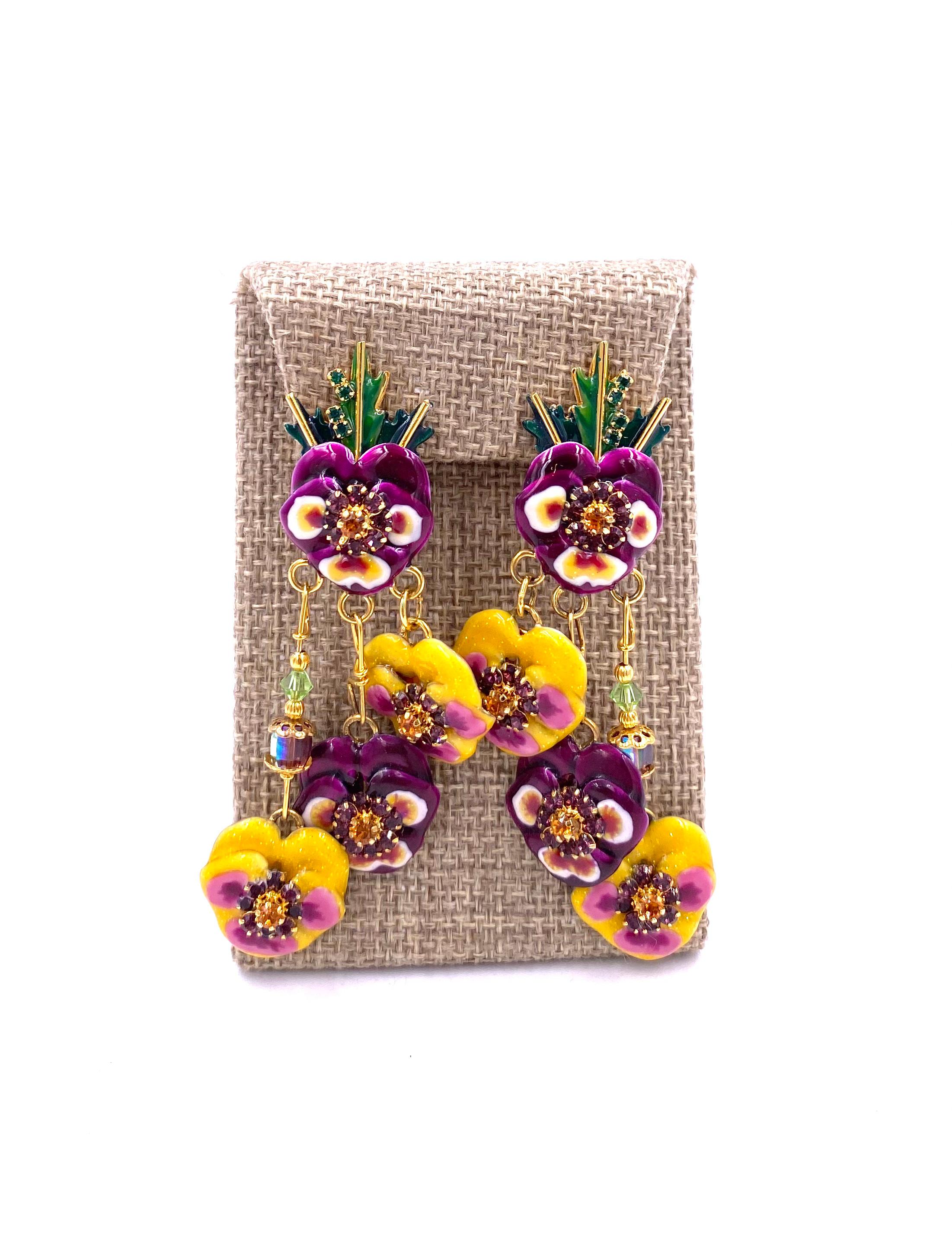 Indulge in the ultimate luxury with our Lunch at the Ritz Earrings in Bunch of Pansies. Adorned with vibrant yellow, magenta, green, and violet flower detailing and sparkling rhinestones, these earrings will add a touch of sophistication and glamour