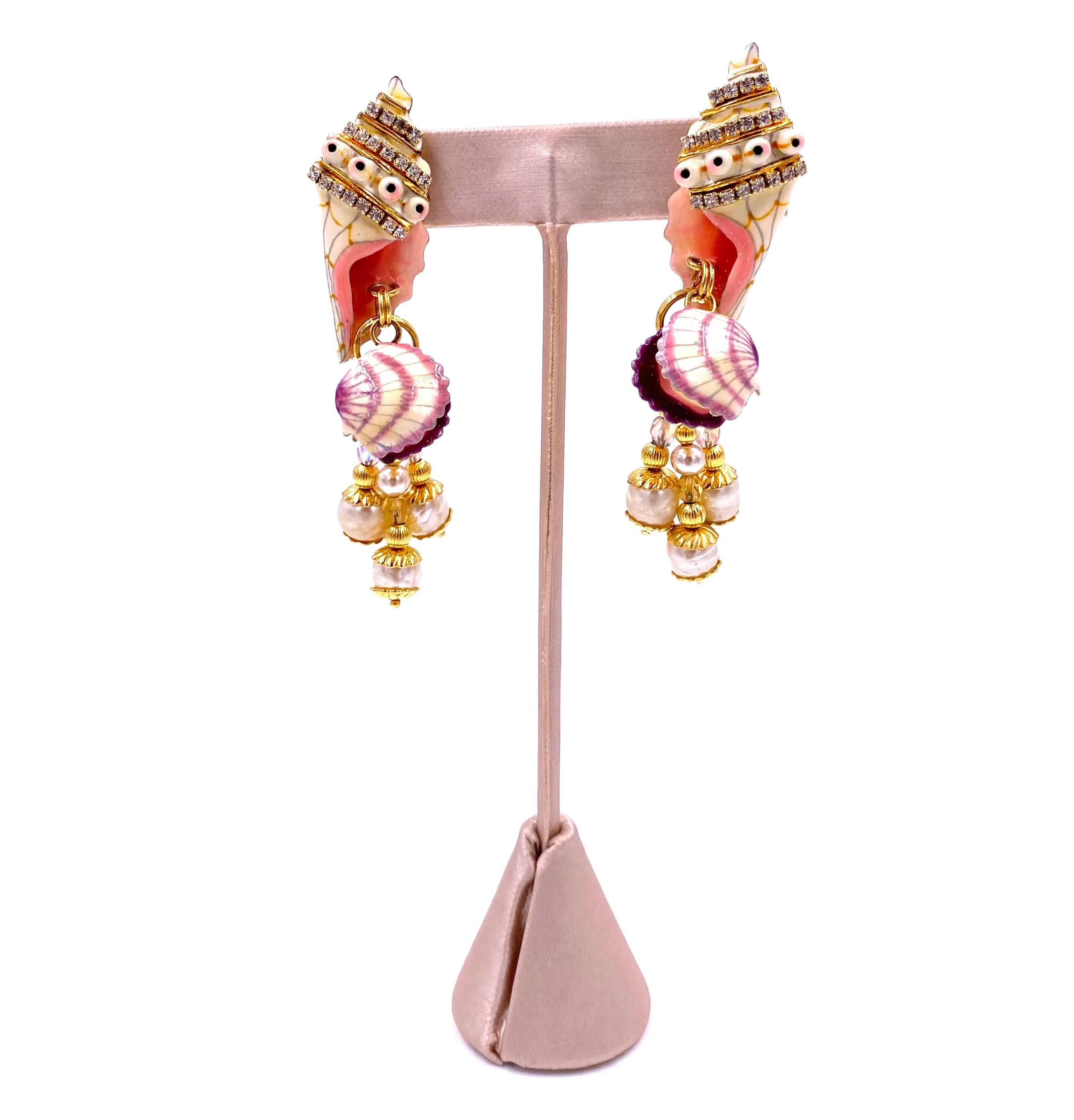 Add some beachy flair to your outfit with the Lunch at the Ritz Clamdigger earrings! These playful pink and purple seashell and clam designs are elevated with pearlescent beads and gold closures. Perfect for a fun and unique touch to any