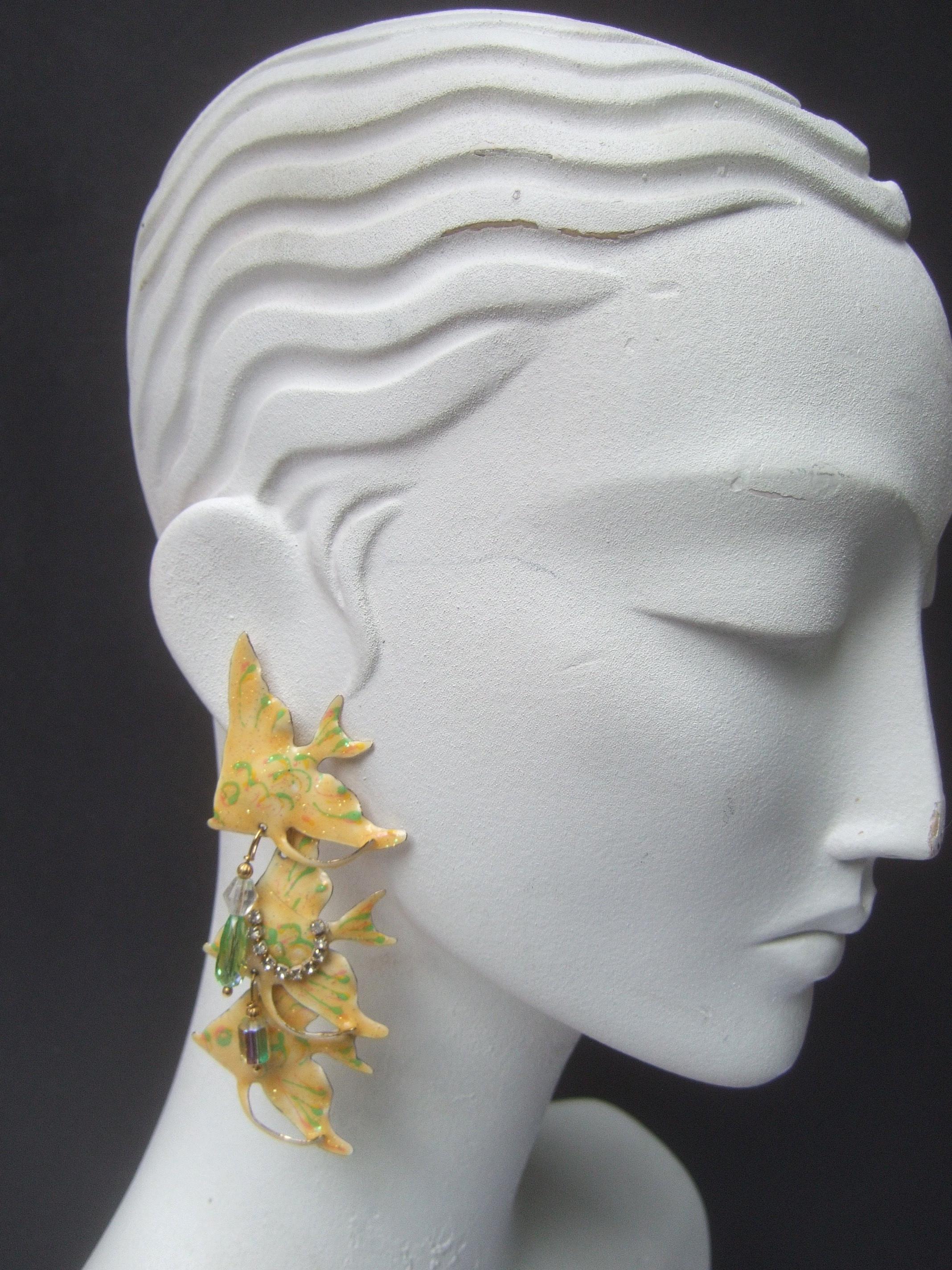 Déjeuner au Ritz - Boucles d'oreilles percées en émail articulé sur le thème du poisson, datant des années 1980
Ces boucles d'oreilles artisanales uniques sont conçues avec un trio de poissons articulés en émail jaune
Accentué par des bandes d'émail