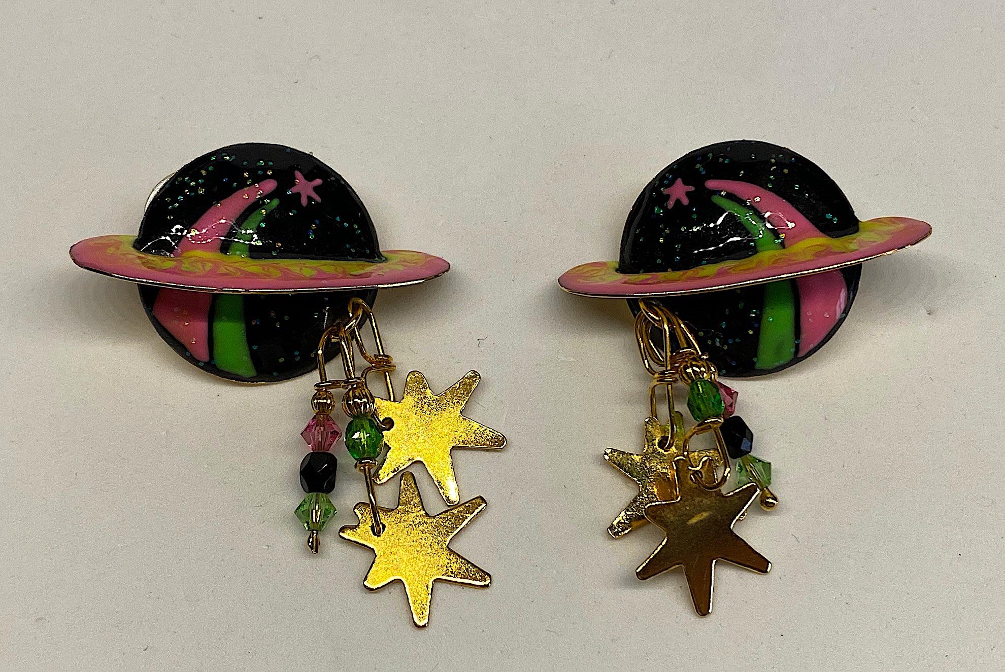 A fun and whimsical pair of Lunch at the Ritz enamel planet saturn earrings circa 1980/90. Each hearing is hand enameled in black, hot pink and green with bits of glitter. There is a right and a left earring. The planet is three dimensional with