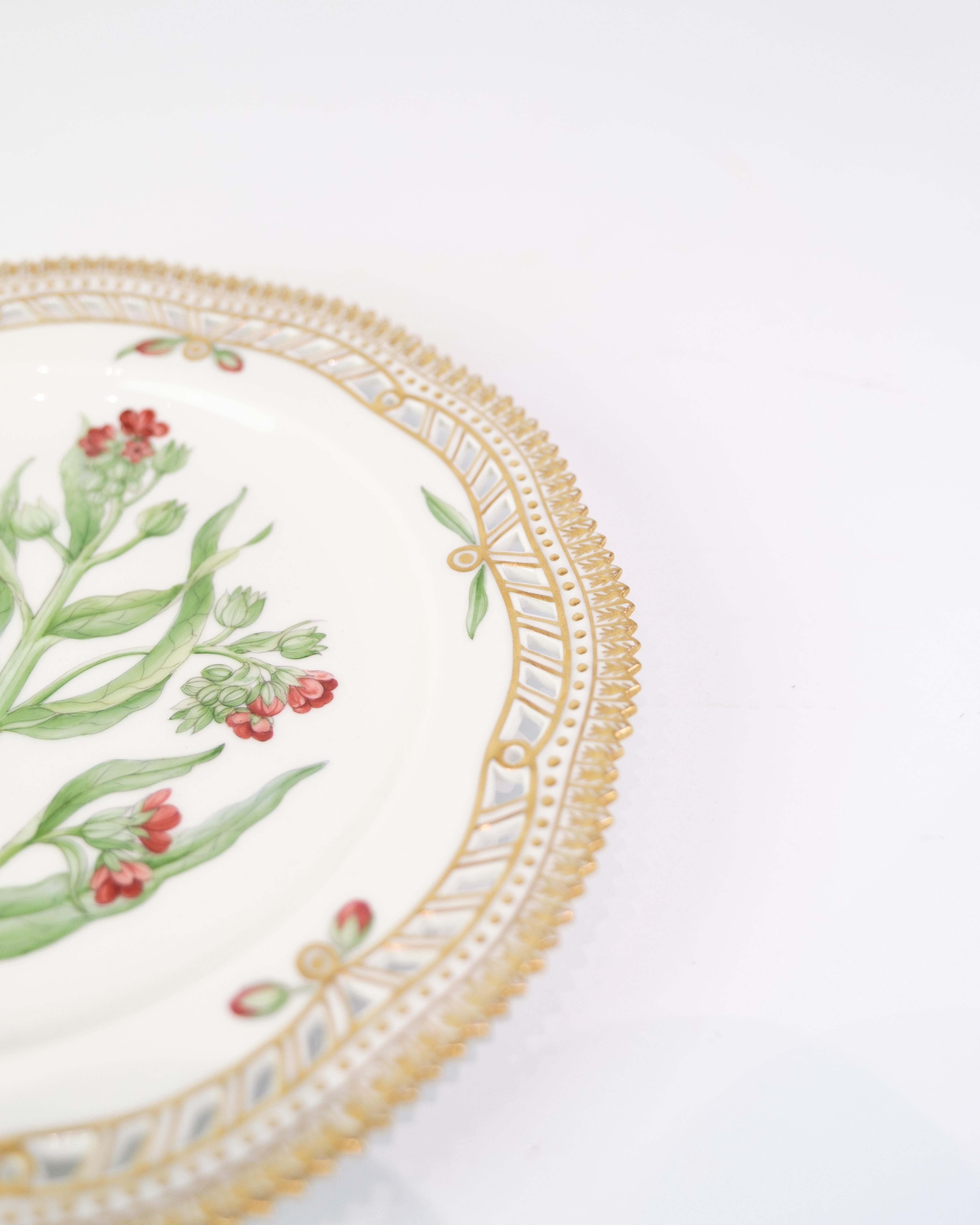 Handbemalter Speiseteller aus der Serie Flora Danica von Royal Copenhagen, hergestellt aus Porzellan und dekoriert mit dem Motiv Nr. 20/3554. Der Teller hat einen durchbrochenen Spitzenrand und eine goldene Oberfläche.

MATERIAL: Porzellan
Dez. Nr.: