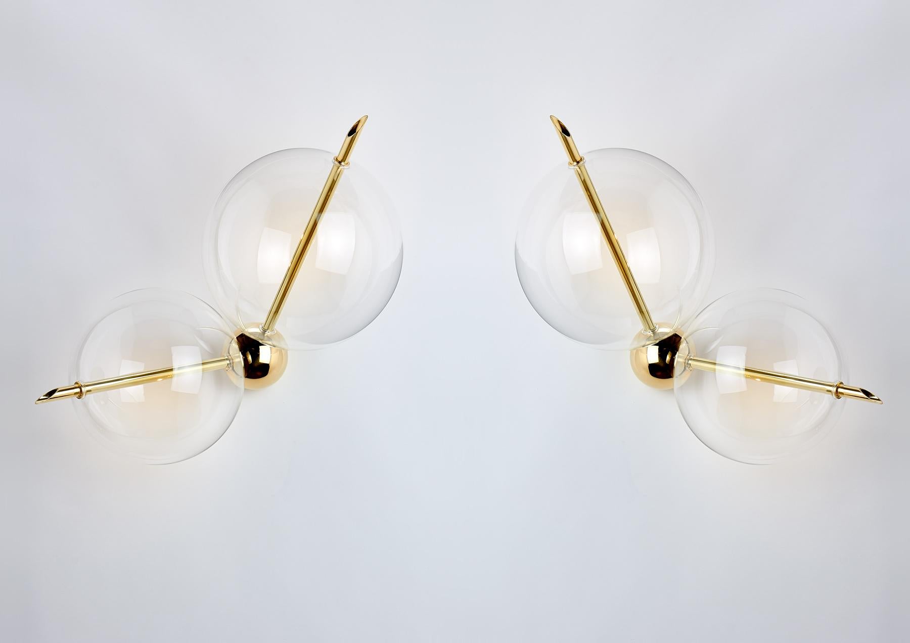 Lune two lights is composed of one solid brass sphere and two handblown glass globes.
The light gets out from the two brass rod crossing over the spheres, and through them, it is diffused softly creating a pleasantly reflecting on the side.
Lune