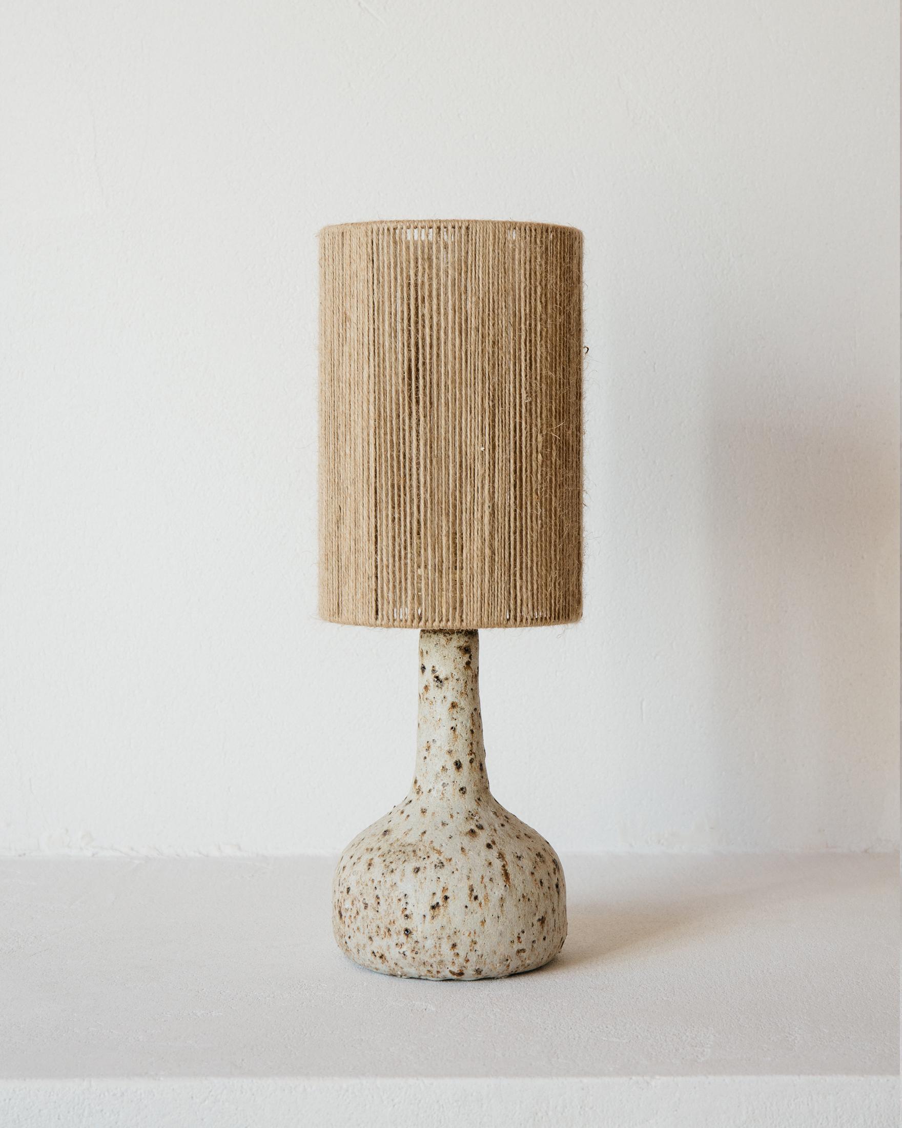 Lámpara de sobremesa de cerámica en bruto Lune de Grès Éditions
Pieza única.
Dimensiones: Pantalla: Ø 16 x A 23 cm.
Base: H 20 cm.
Materiales: Yute y cerámica.
Peso: 1,2 kg.

Sistema eléctrico: cable eléctrico tejido de lino (longitud: 150 cm),