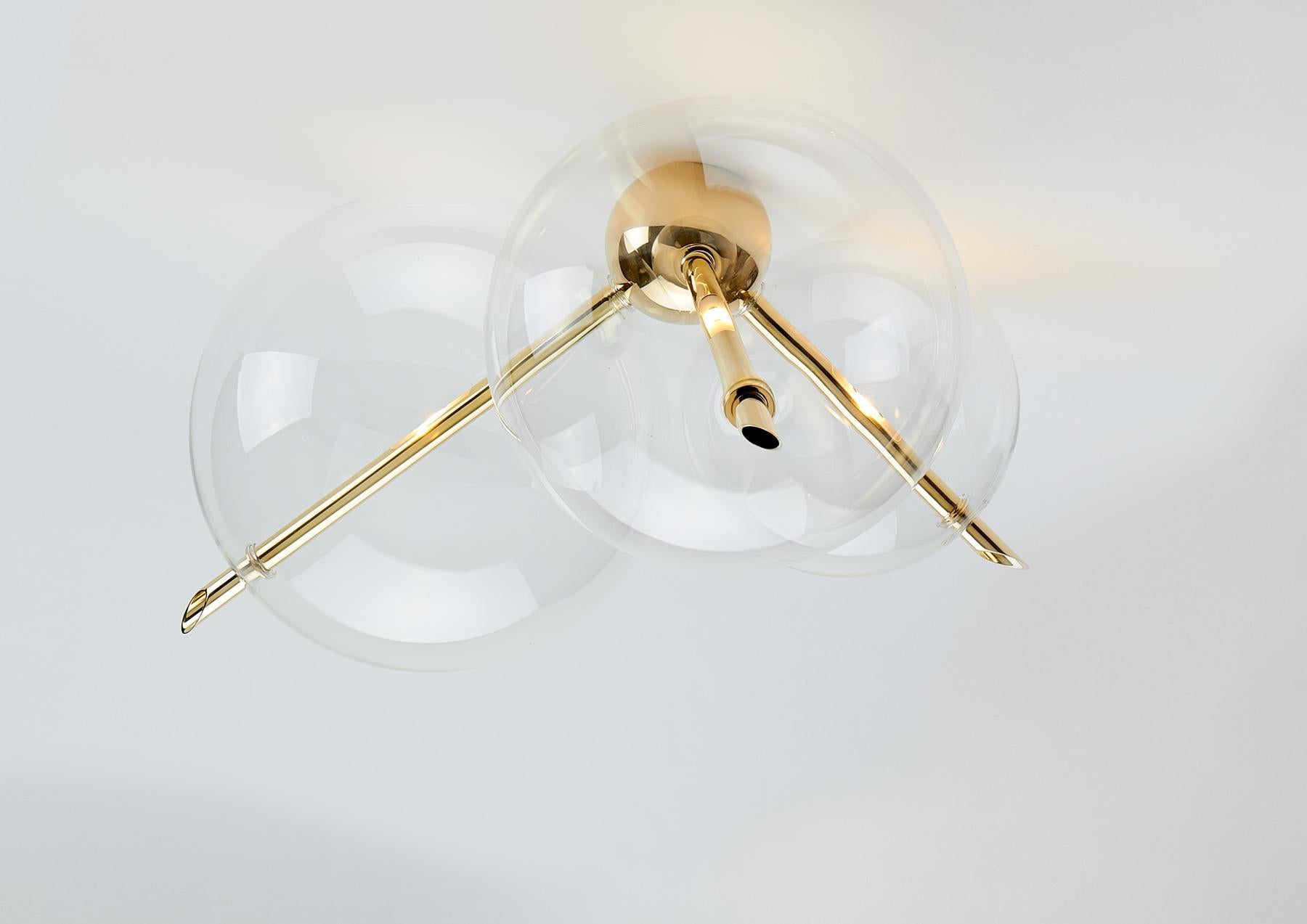Lune Three Lights, suitable as a Wall Light or Ceiling Mount is composed by a solid Brass Sphere and  Three Hand-Blown Glass Globes.
The Light gets out from the three Brass rod crossing over the spheres, and through them, it is diffused softly