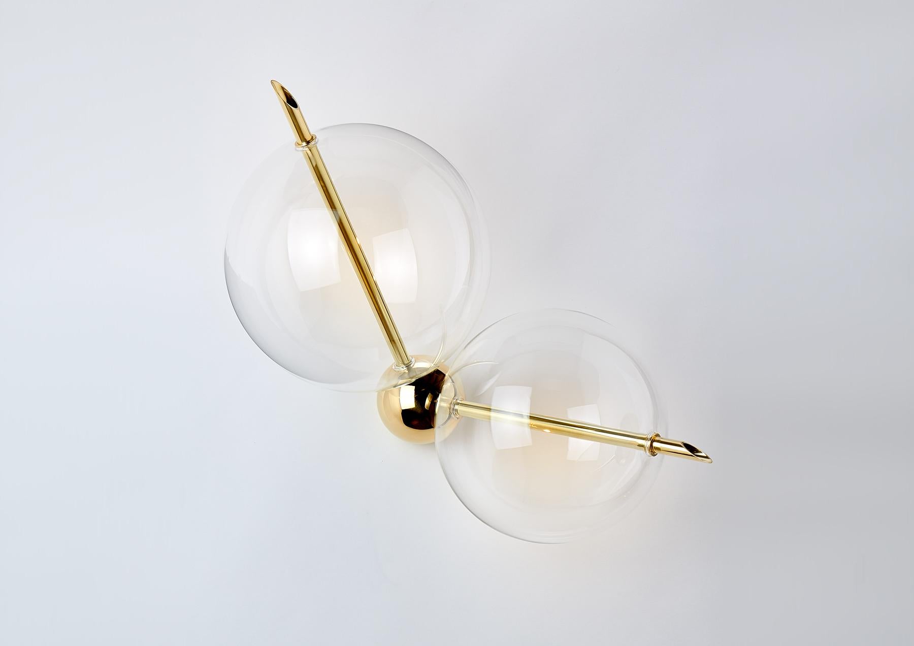 Lune Two Lights is composed by a solid Brass Sphere and  Two Hand-Blown Glass Globes.
The Light gets out from the two Brass rod crossing over the spheres, and through them, it is diffused softly creating a pleasantly reflecting on the side.
Lune