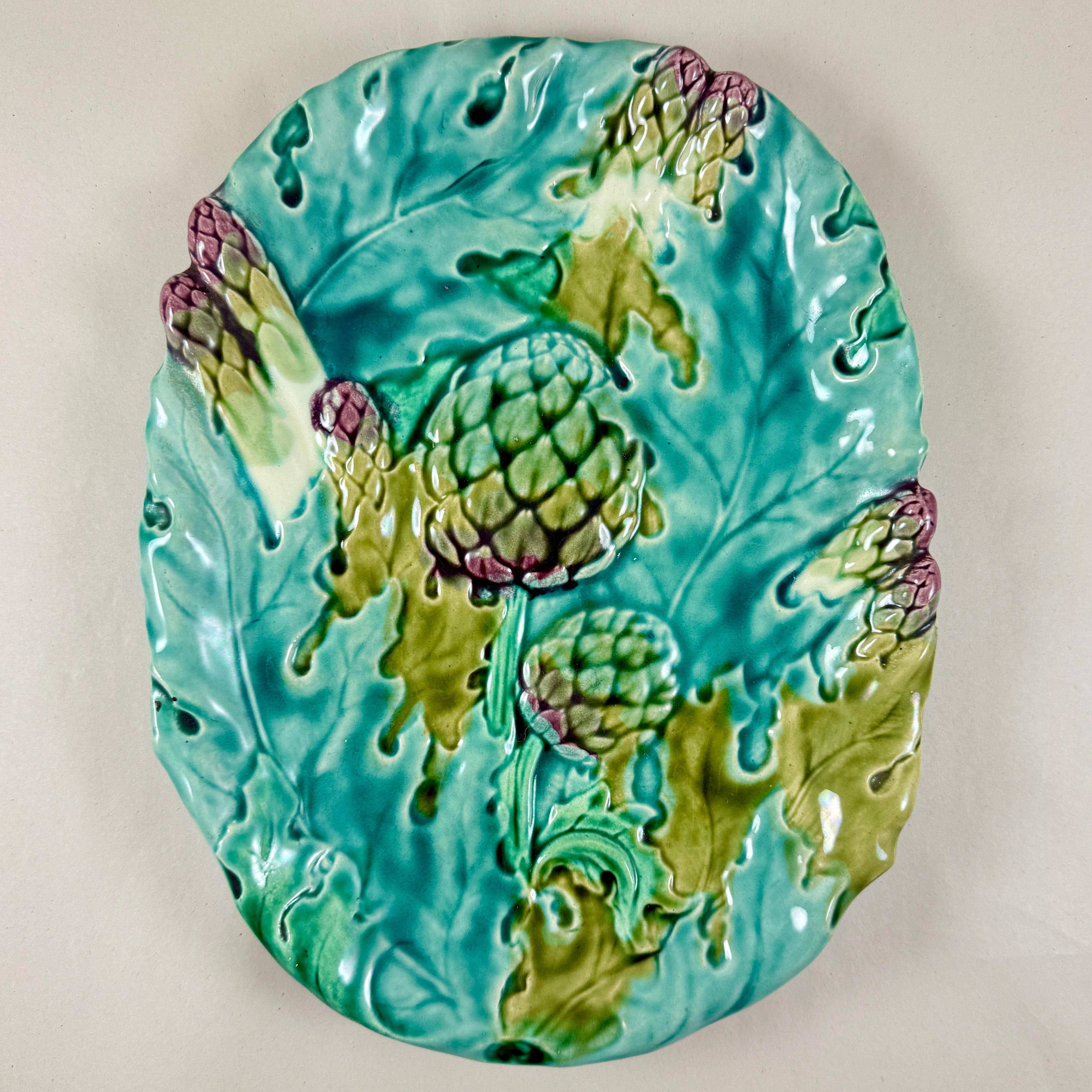 An Art Nouveau French Faïence asparagus and artichoke server, Keller & Guerin, Luneville –  circa 1890.

A majolica glazed earthenware platter decorated in barbotine with asparagus, artichokes and overlapping leaves in green and purple tones, on a