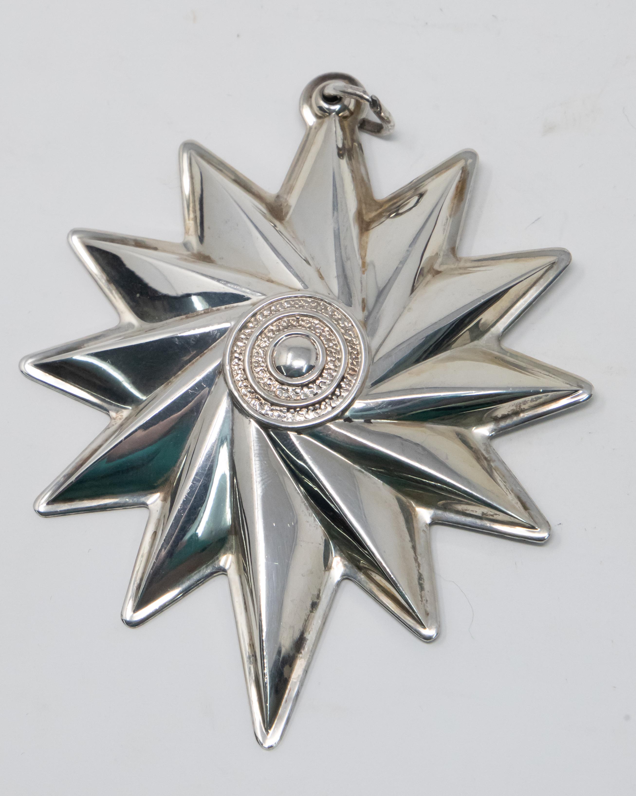 Offering this stunning Lunt sterling spiral star ornament from 1999. Starting in the center with a bullseye with punch work between the rings. From there go outward in a geometric spiral pattern. Simple lines make this piece dance in your eyes.