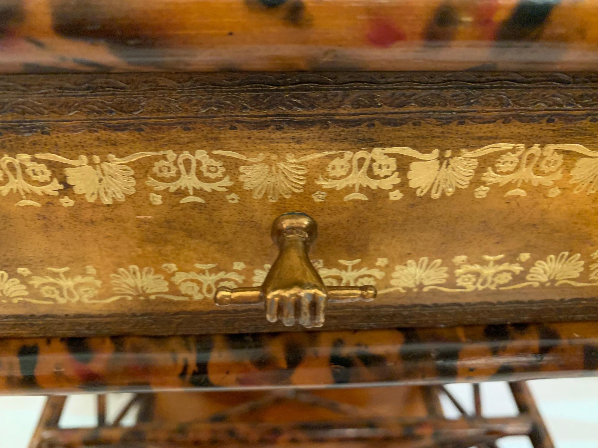 Gorgeous caramel colored tooled leather and bamboo side table and canterbury magazine rack having single drawer and brass embellishments including a stunning handle in the shape of a hand.