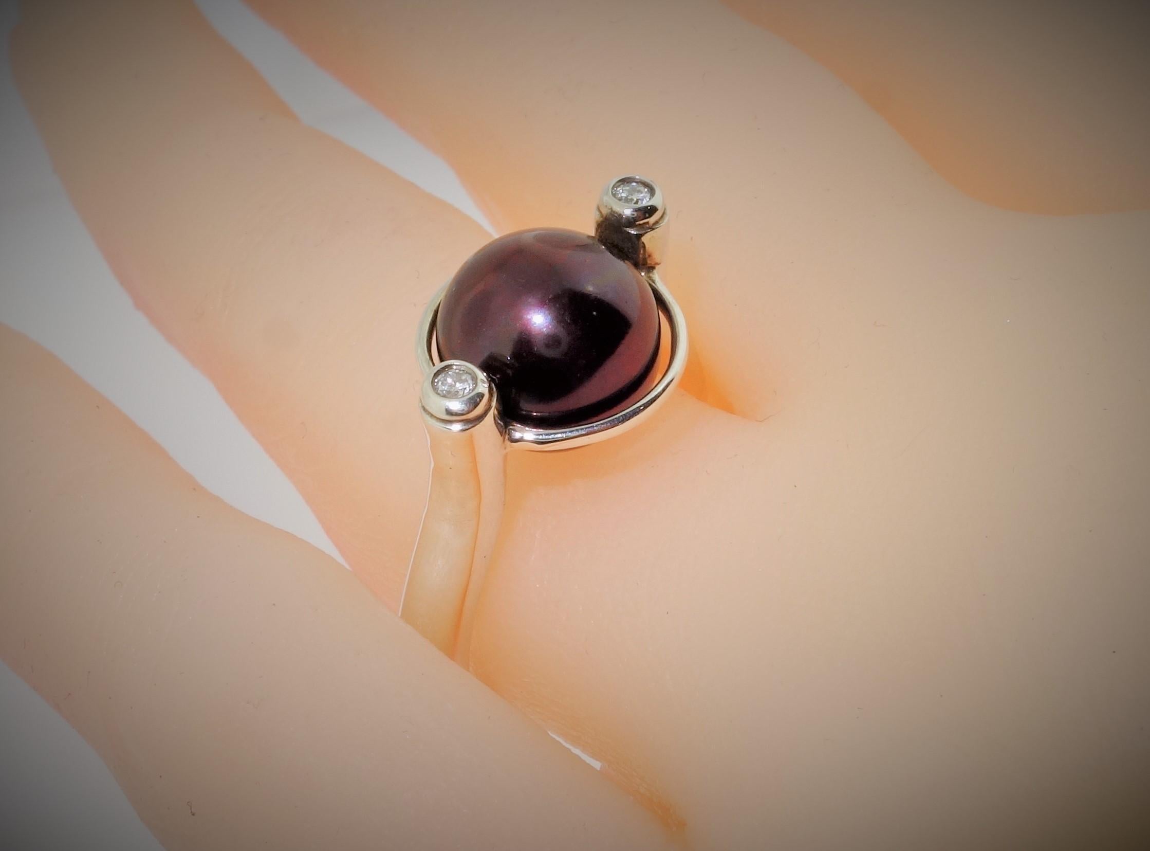 Fabulous ring featuring a 10mm freshwater Luscious Chocolate Pearl in center enhanced with a round brilliant cut diamond either side; approx. .10tctw; Sterling Silver Rhodium Tarnish-resistant mounting. Size 6.5; The perfect accessory for the modern