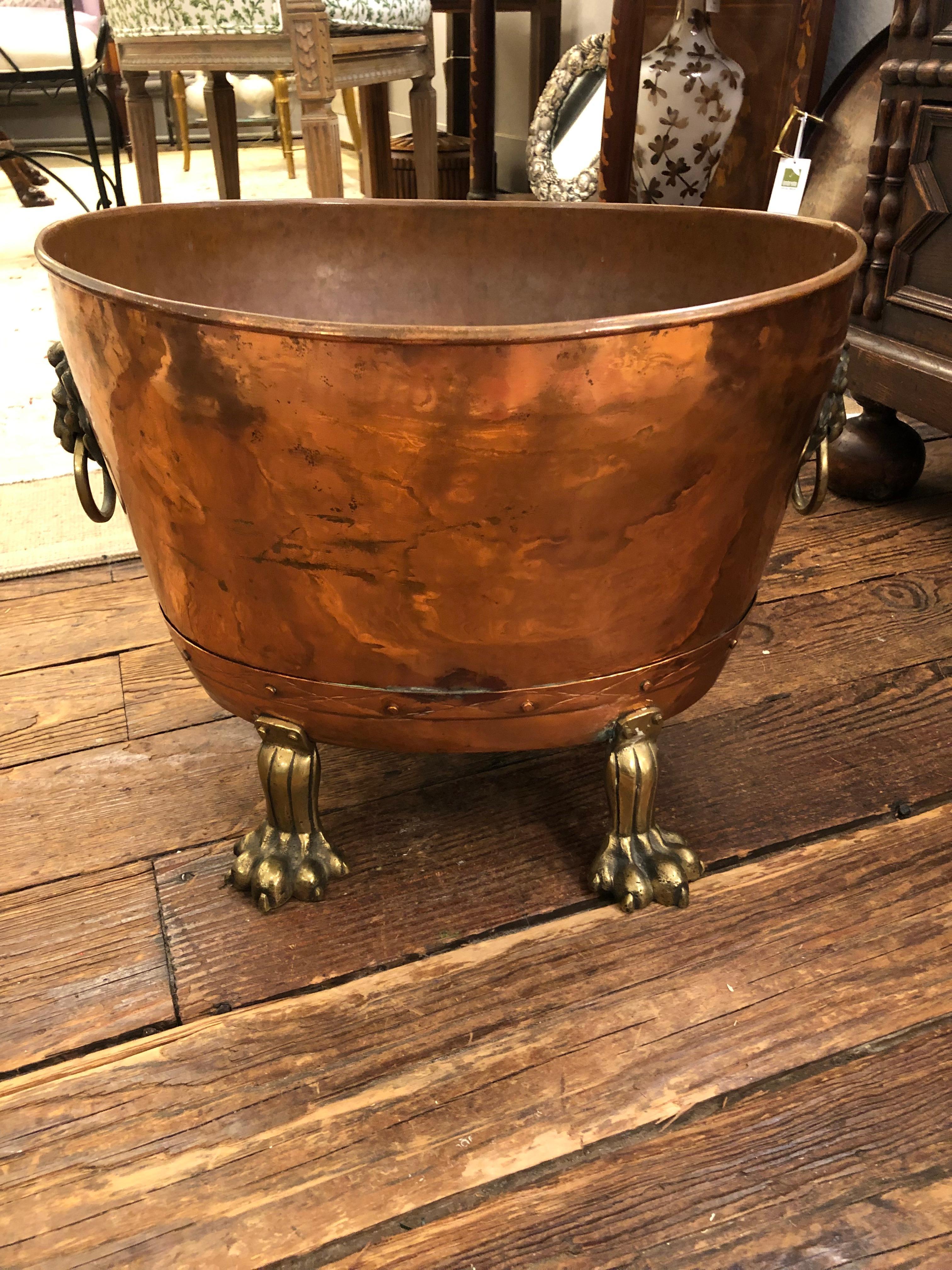 Gorgeous antique copper log kindling holder having an oval shape and fantastic brass lion ring holders on each side and large paw feet. Beautiful enough to hold magazines or be used as a centerpiece filled with a plant or decorative branches.