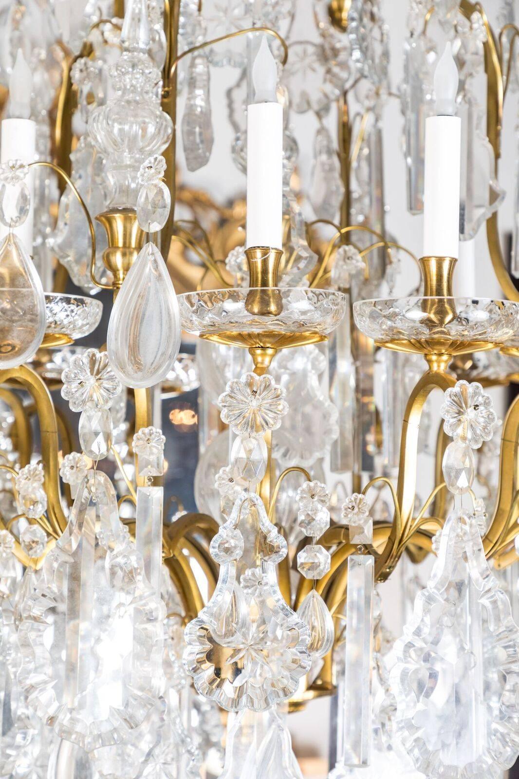 Reich verzierter, großer, vergoldeter Bronze- und Kristallkronleuchter im Louis-XIV-Stil mit zwölf Lichtern und einem großen, zentralen Turm. Das Ganze wird von einem beeindruckenden, kristallbesetzten, ballonförmigen Baldachin gekrönt.