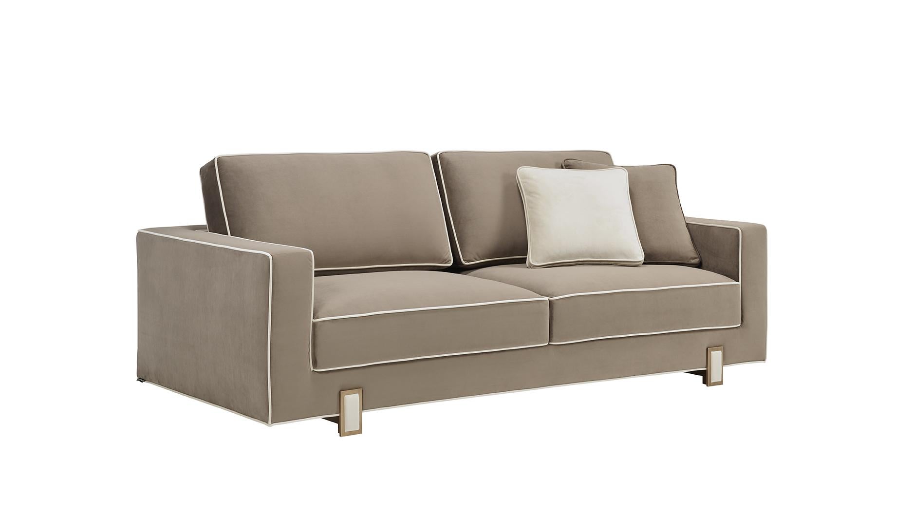LUSO sofa is a very delicate piece, with special details, designed to be used on a daily basis. Upholstered with two fabrics, using a contrasting piping for an refined result. The feet, in antique brass color, have a fabric detail at the center,