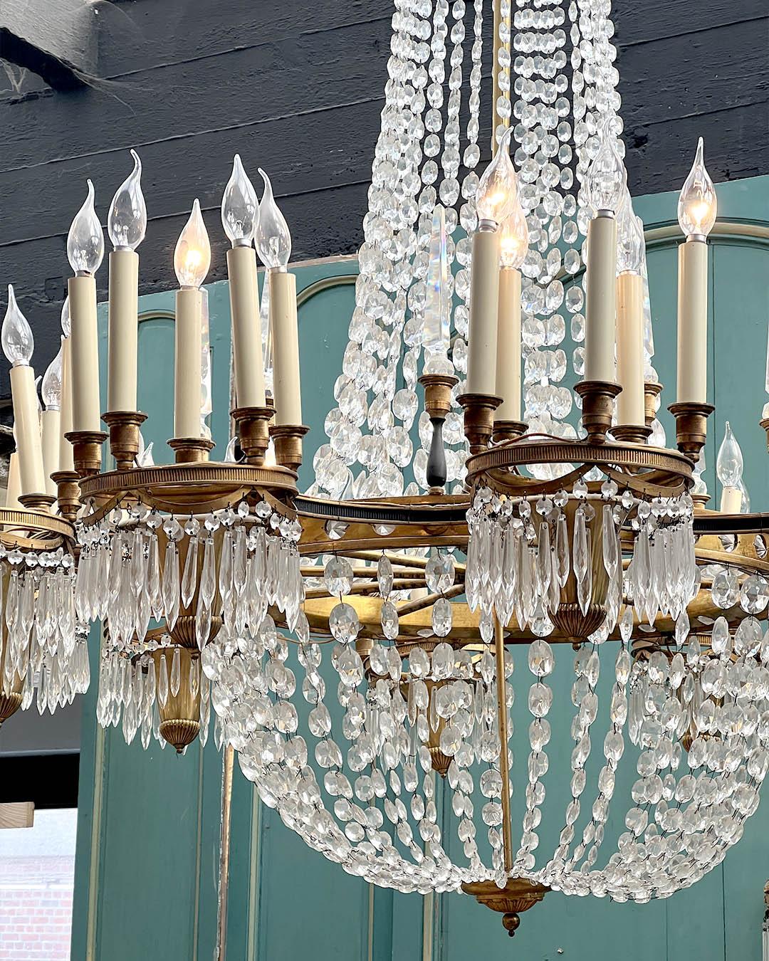 A sublime chandelier with an impressive 140 cm diameter. This gilded brass chandelier is adorned with cut glass pendants, providing a shimmering light and majestic elegance.
The ensemble consists of two crowns supporting brass arms adorned with faux