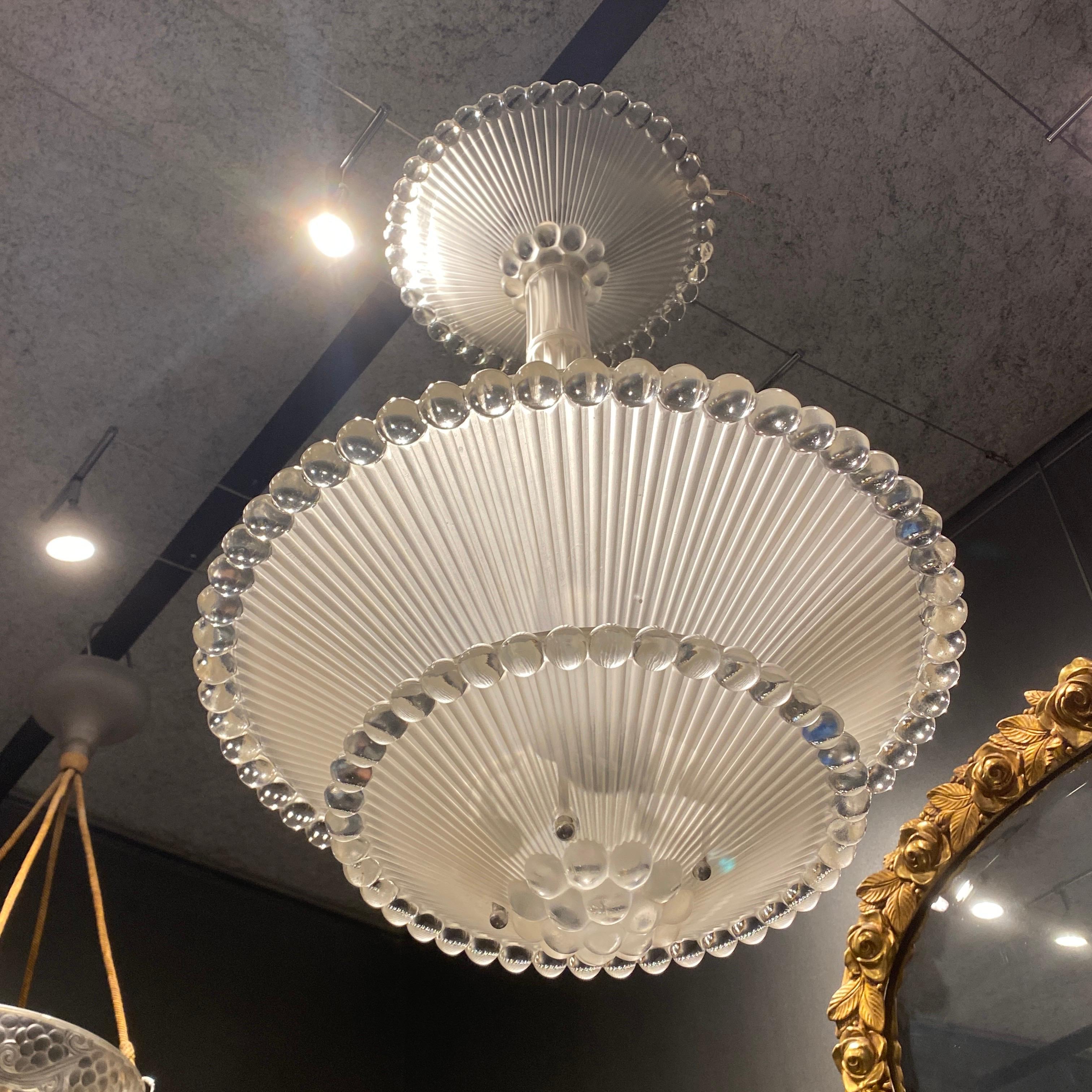 The perles glass chandelier is made by R.Lalique en white glass in 1931.

It is consisting of 3 different glass bowl, plus a glass central tube.

The signature is molded and sand blasted block letters.

The electrification has been redone, the