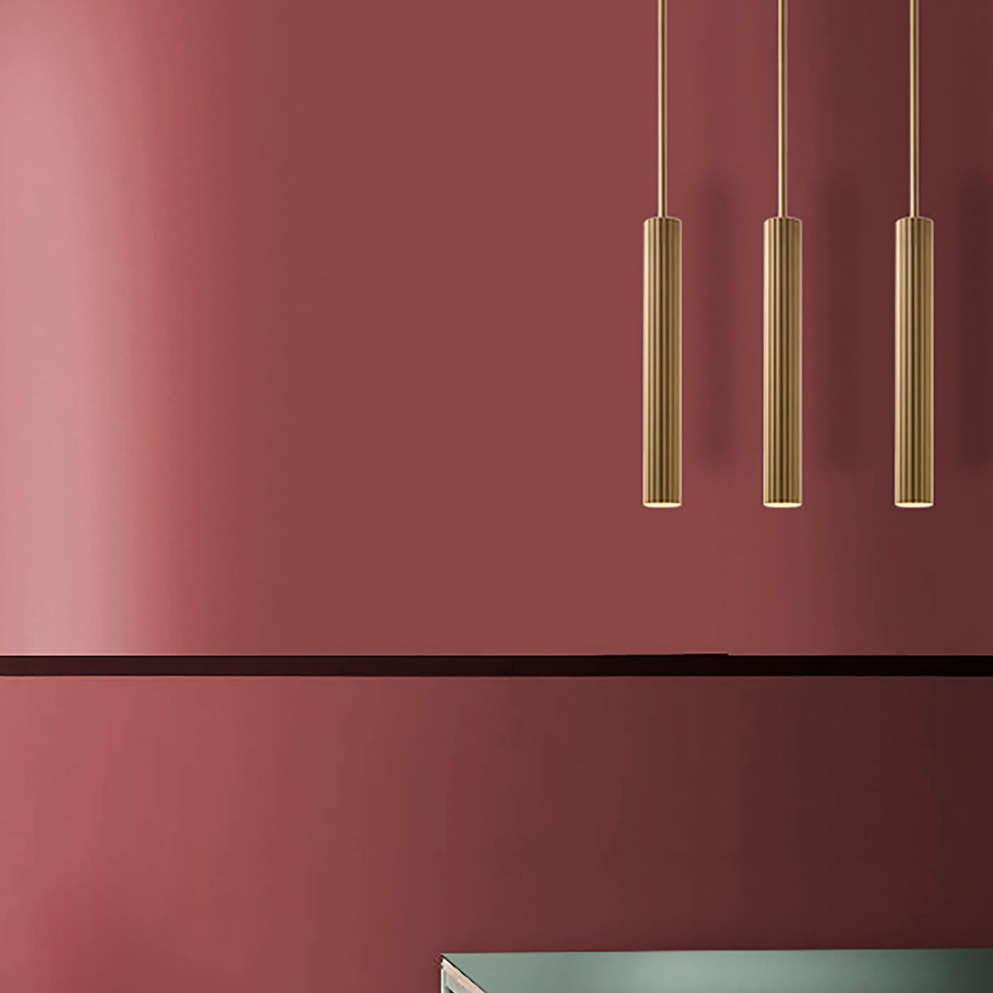 Elegant and linear, this pendant lamp designed by Isacco Brioschi is striking for its surface, worked to become soft and shiny as silk. Light becomes tangible, thanks to the brass cylindrical diffuser in a champagne gold finish with vertical striped