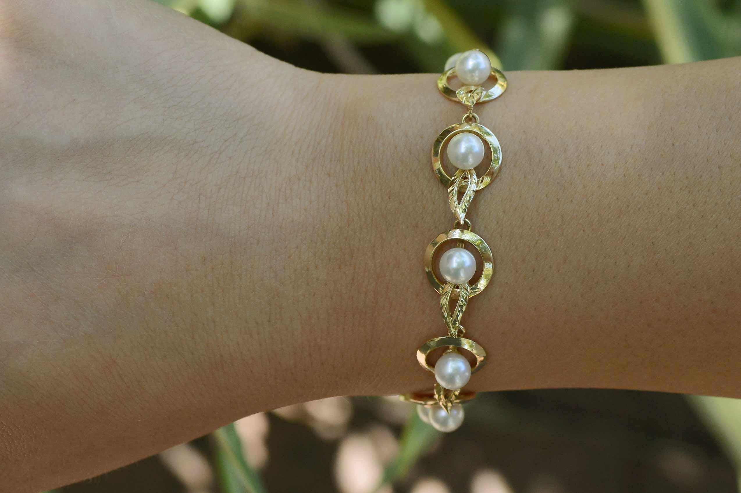 An alluring Art Deco pearl link bracelet of buttery, glowing yellow gold encircles your wrist with 11 perfectly round, top rose color cultured pearls. A clever take on the classic target design, this geometric wonder is embellished by engraved