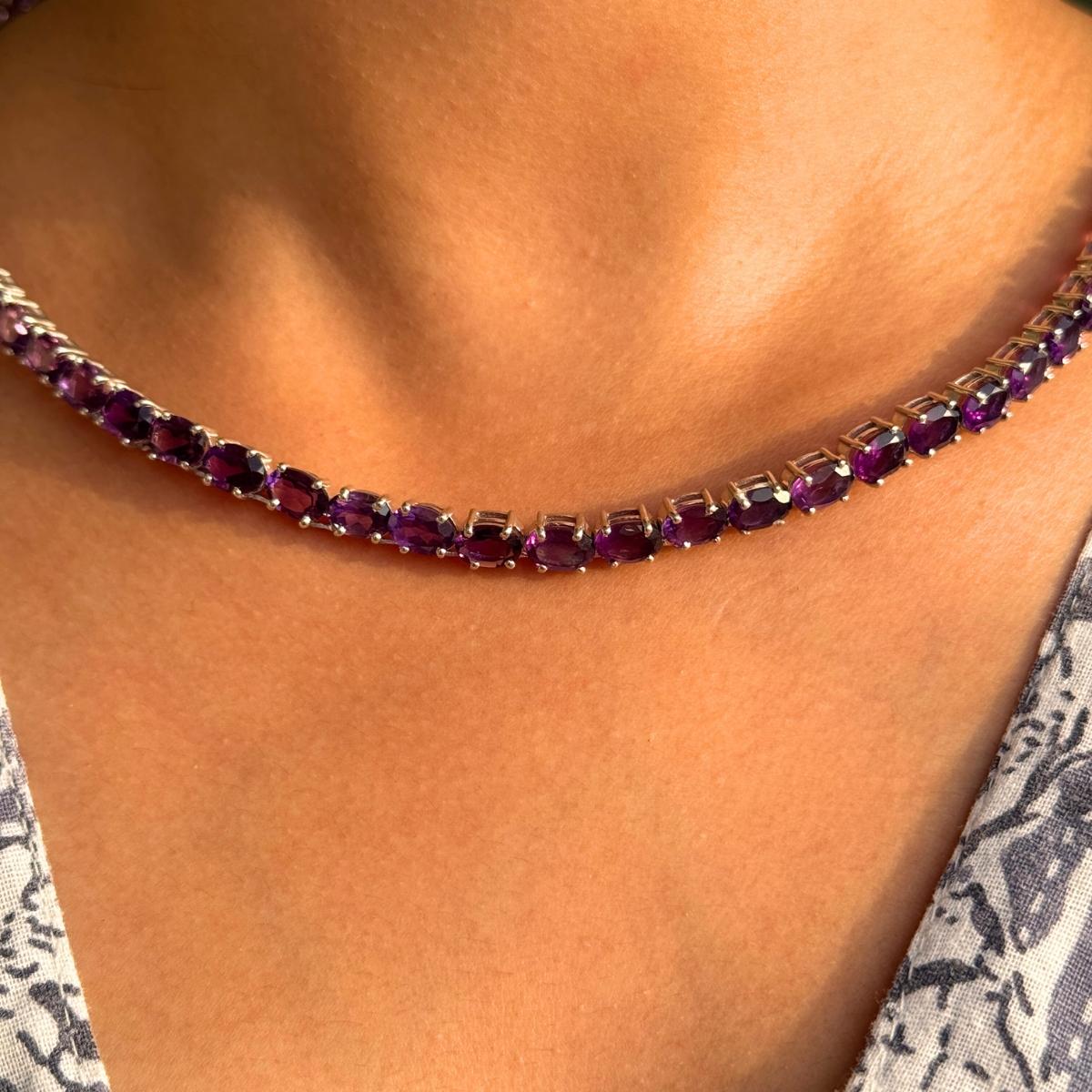 Questa collana da tennis con gemme ovali di ametista è un gioiello di lusso da regalare con un filo continuo di gemme ovali di ametista, riccamente saturate, incastonate a mano nell'argento 925. Le profonde sfumature viola brillano con intensità,