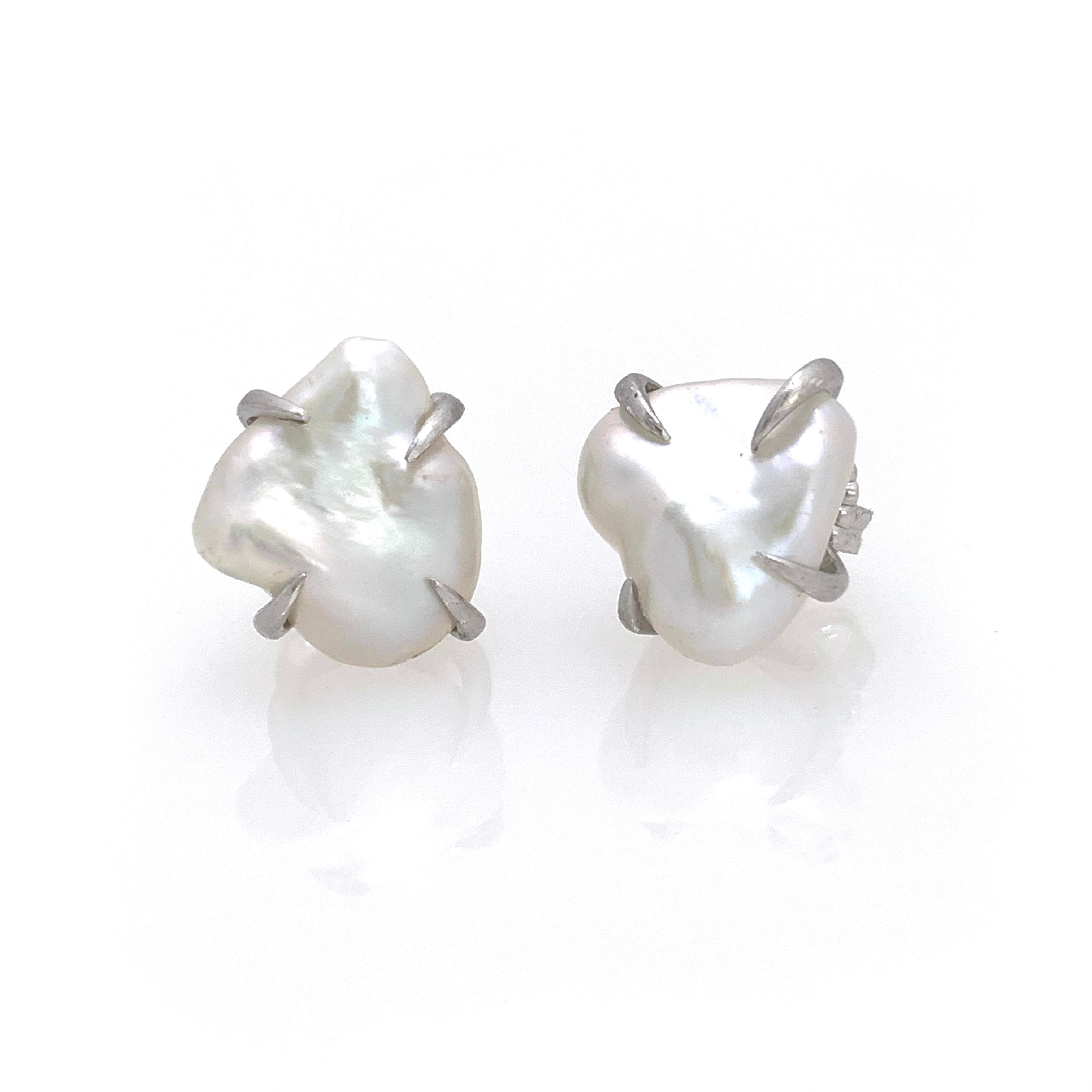 Beautiful pair of lustrous white baroque pearl stud earrings. The pair measures 12-13mm width, handset in platinum rhodium plated sterling silver (matte finish). Straight post with large friction back allowing the earrings to sit well on the ear.